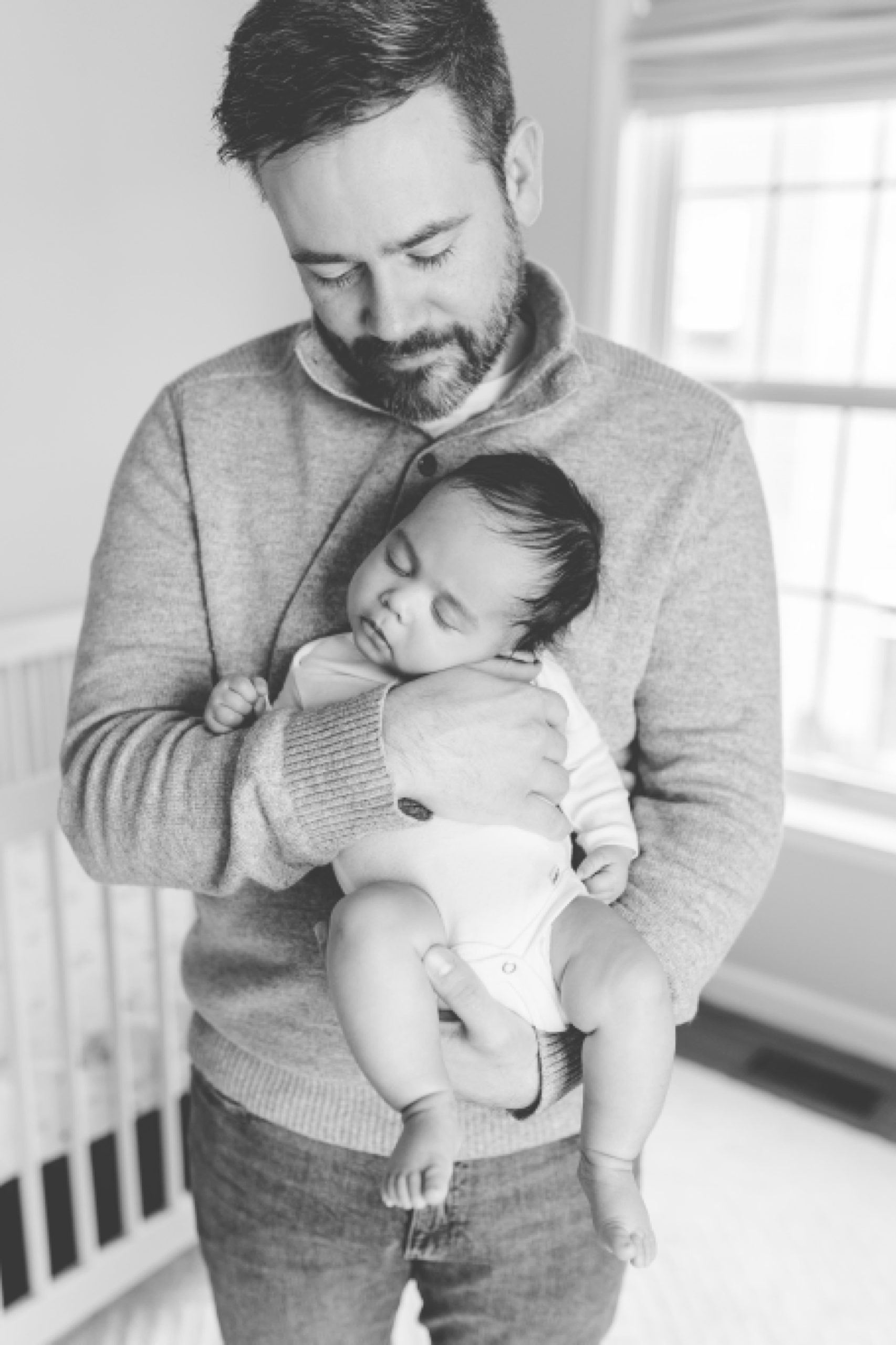 dad holds older newborn in front of his chest during portraits at home