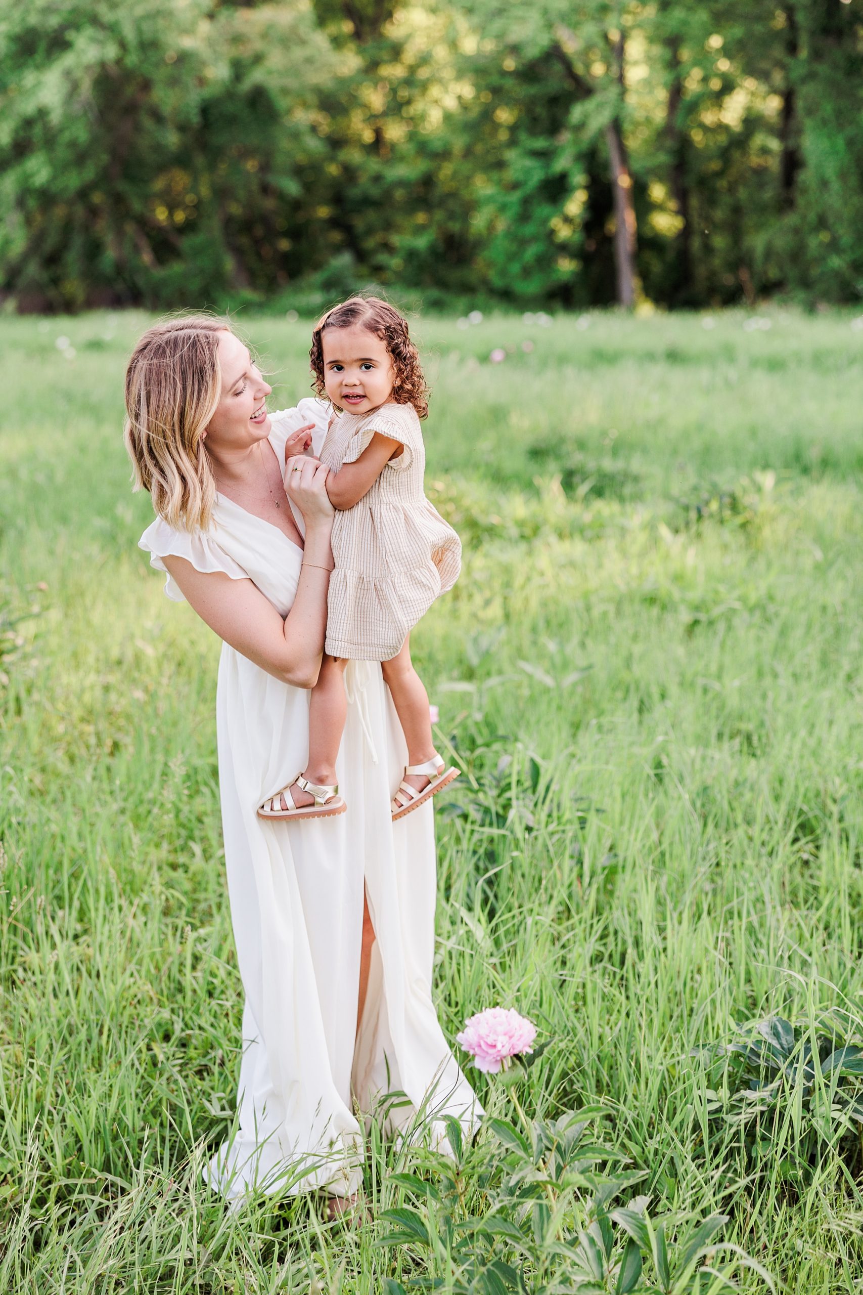 mom plays with daughter during family photos in peony field