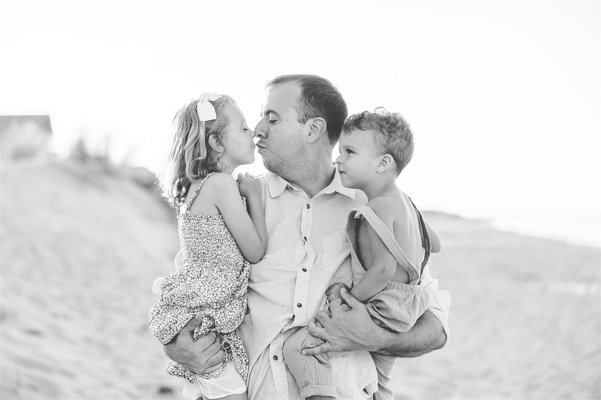 black and white photo of dad holding two kids on Delaware Beach