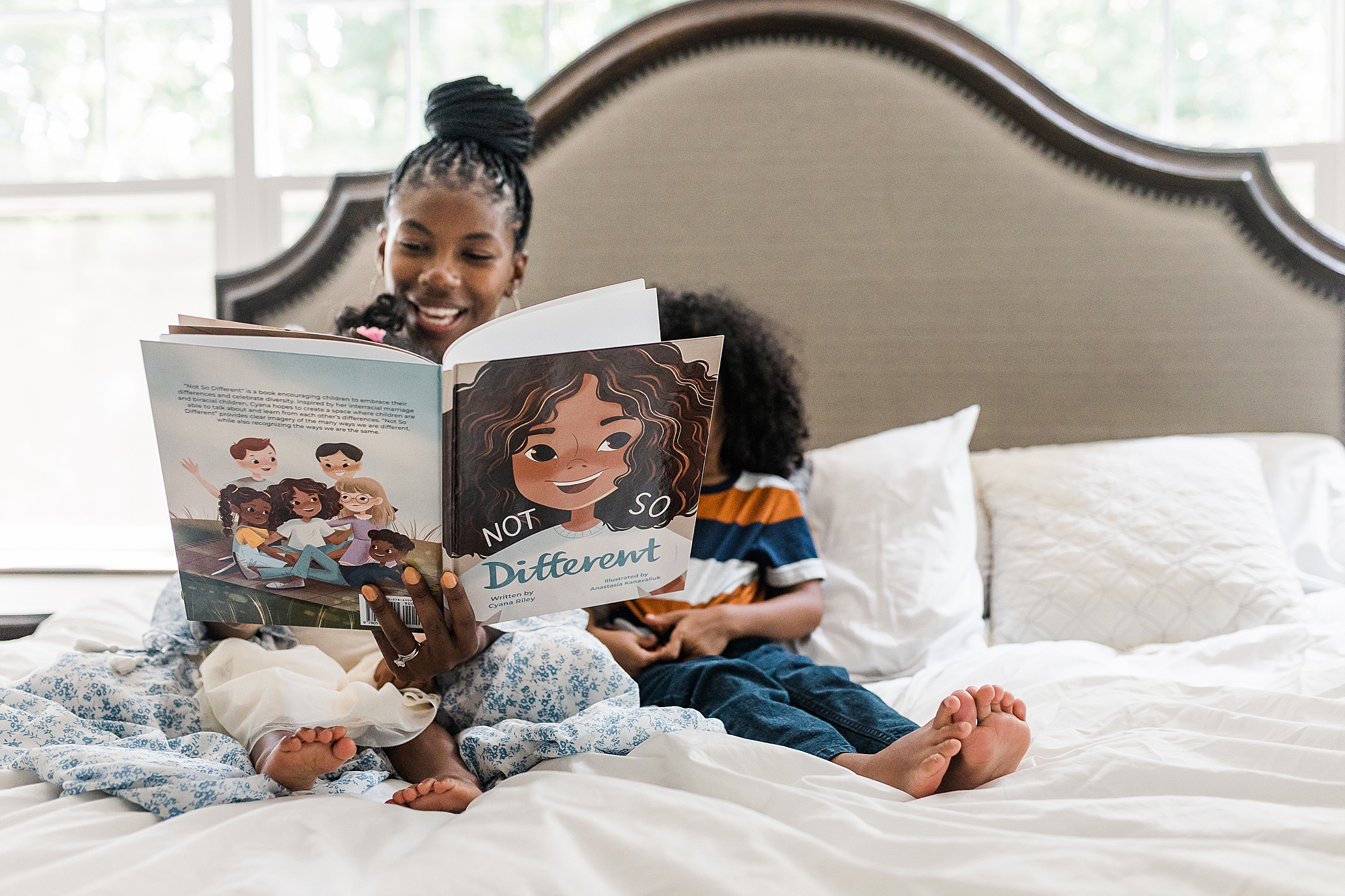 mom sits on bed reading book to children