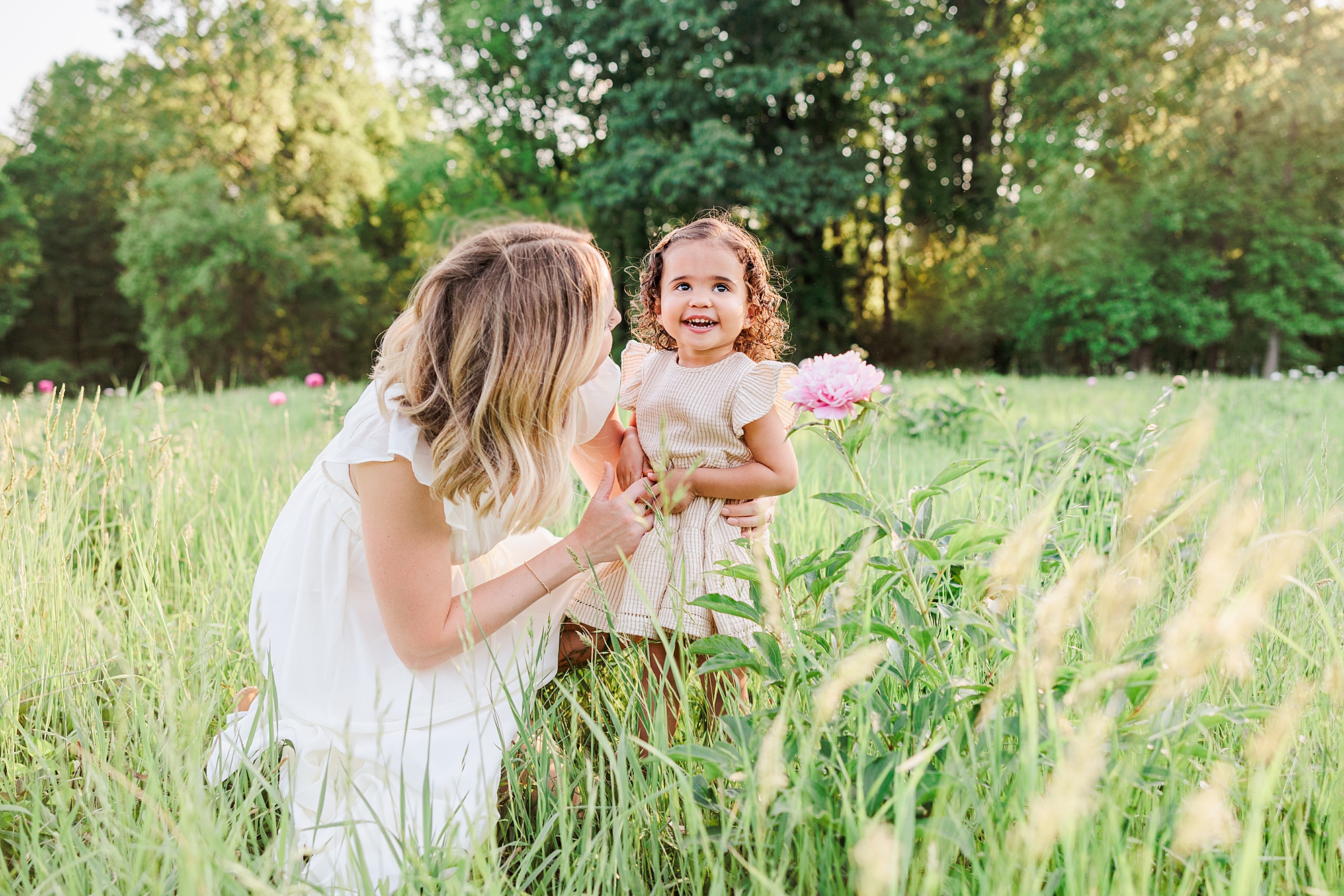 mom poses with daughter in neutral spring outfits in grass