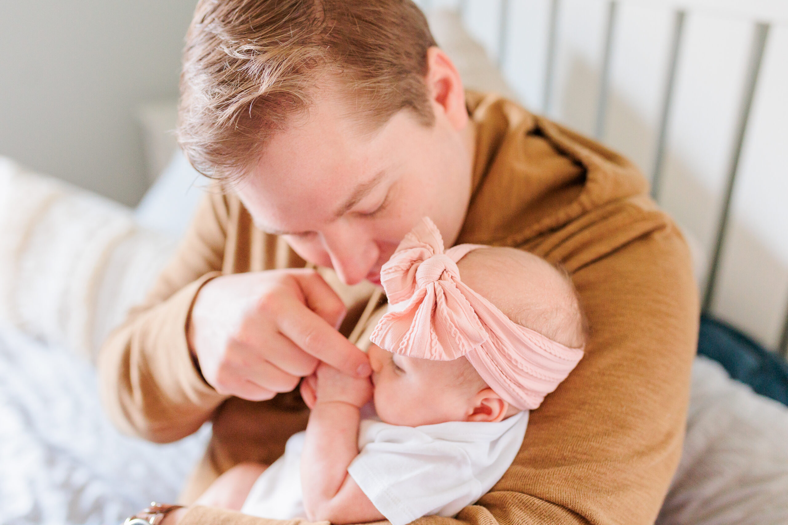 dad kisses baby girl's cheek during lifestyle newborn photos