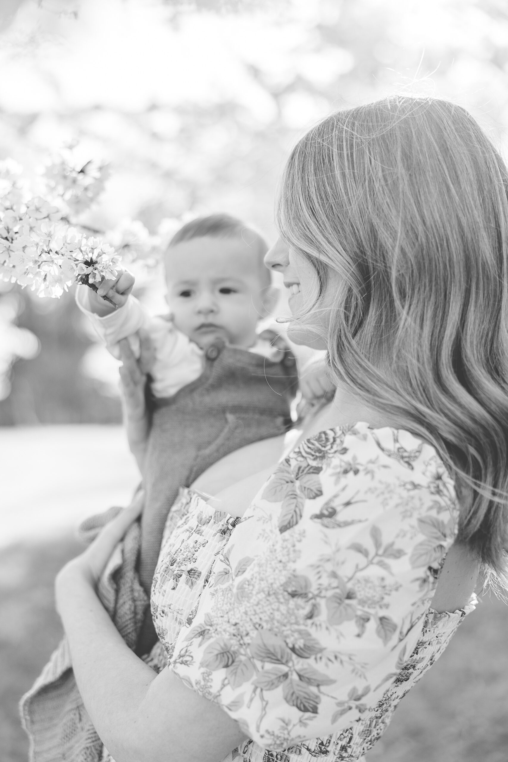 mom holds baby to reach flowers during family photos in the DMV