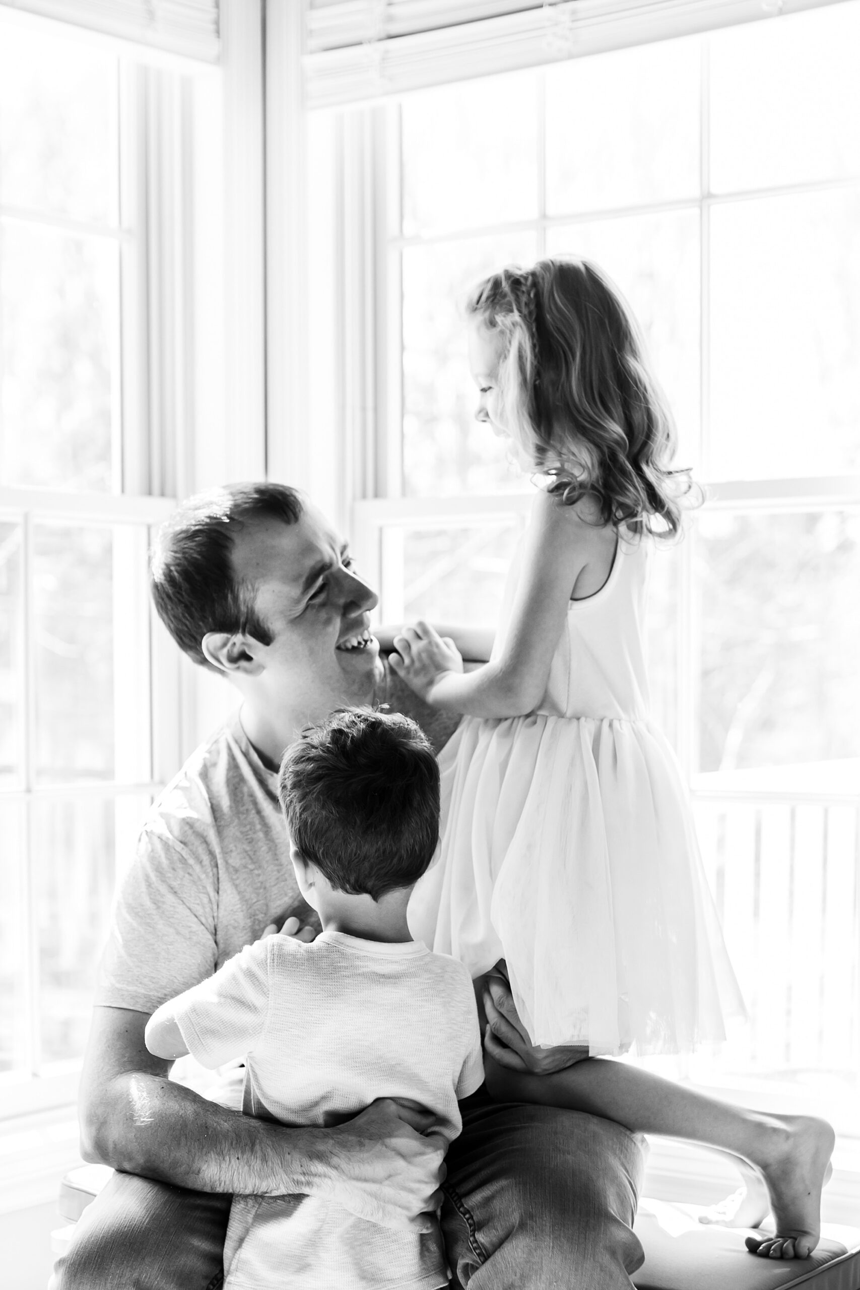 dad hugs daughter and son by window during Maryland lifestyle family photos