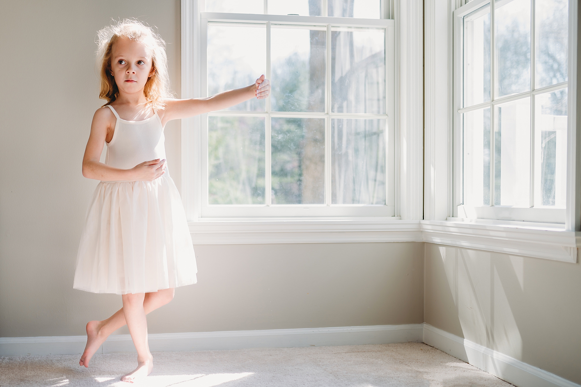 girl poses by open windows in Maryland home in white dress