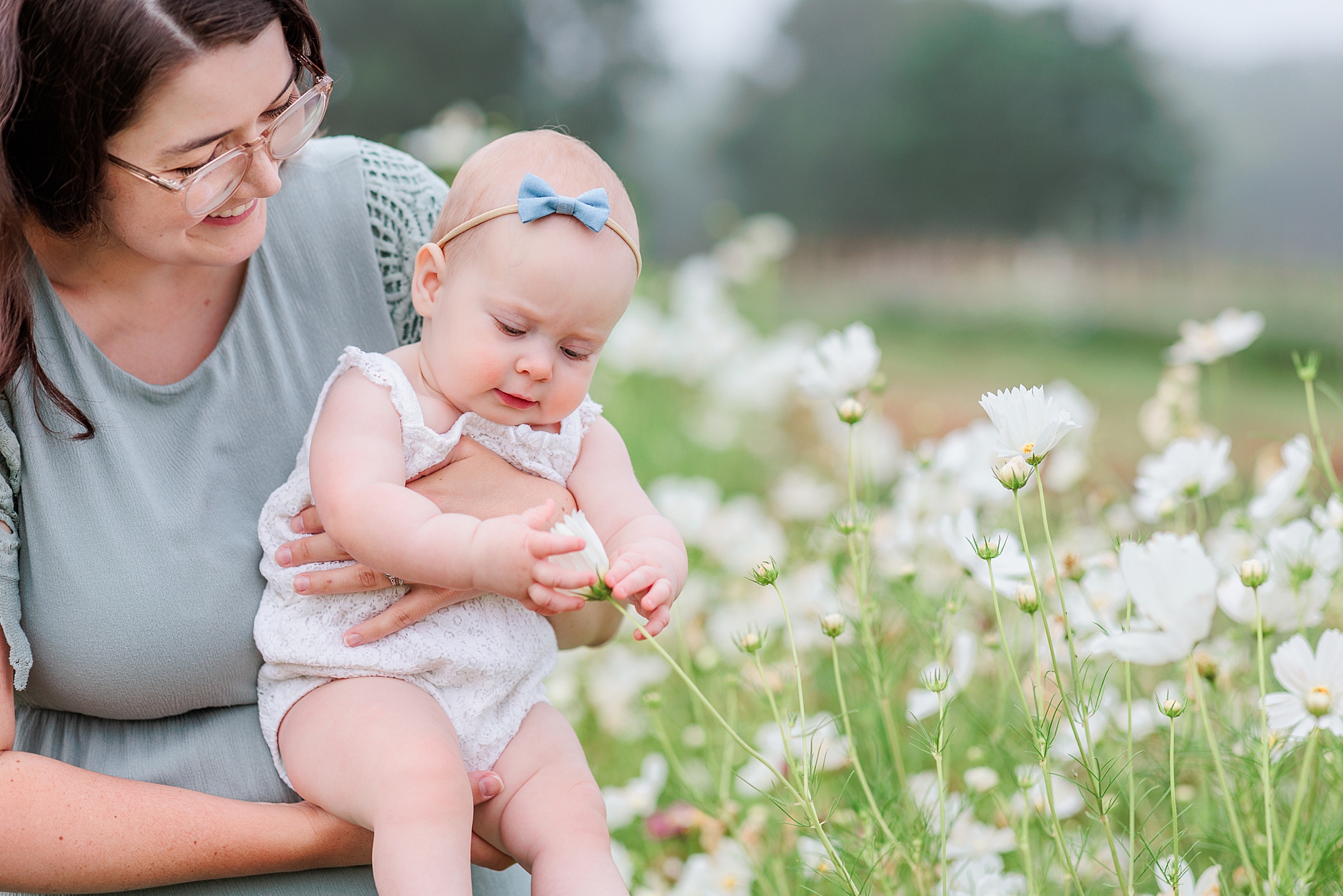 toddler holds flower between fingers during mom and me photos at Castlebridge Farm