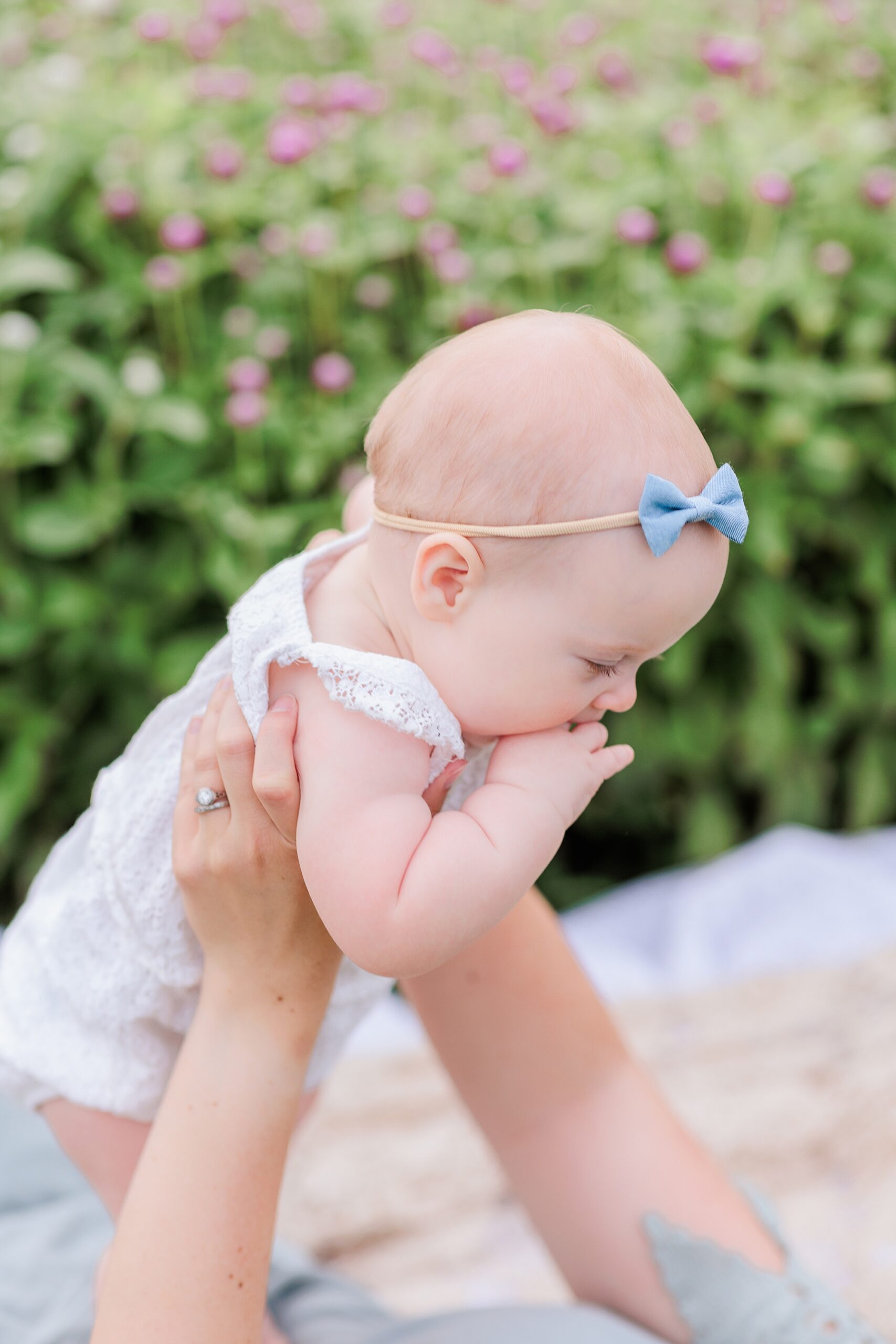mom lifts up baby girl in white romper during mom and me photos at Castlebridge Farm