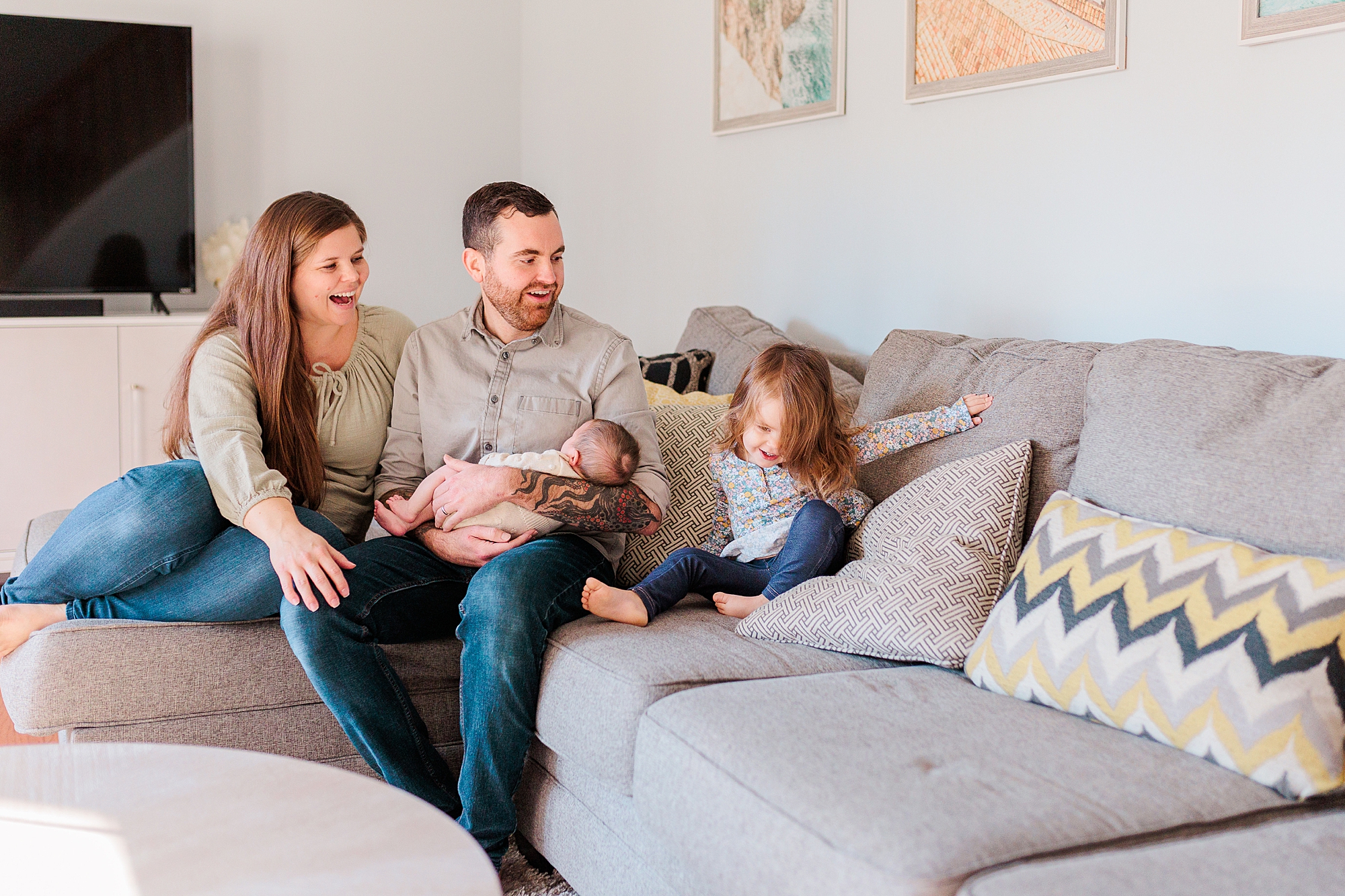 toddler talks to parents sitting on couch in living room during Maryland newborn lifestyle photos