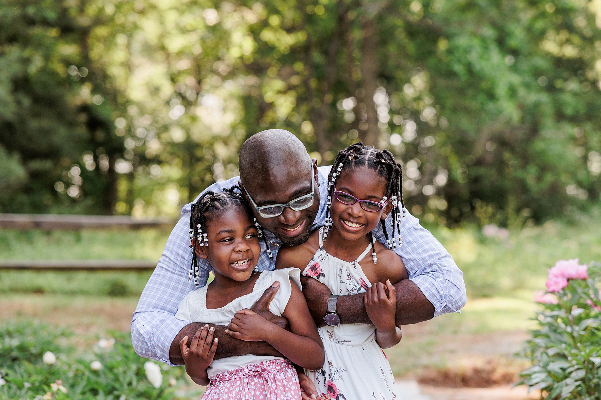 dad hugs two daughters in peony field during Maryland family photos