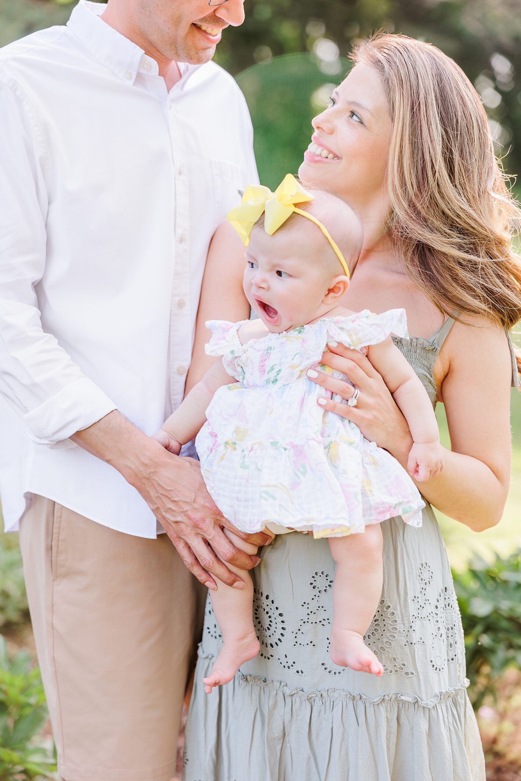 woman holds daughter smiling at husband during peony field mini session