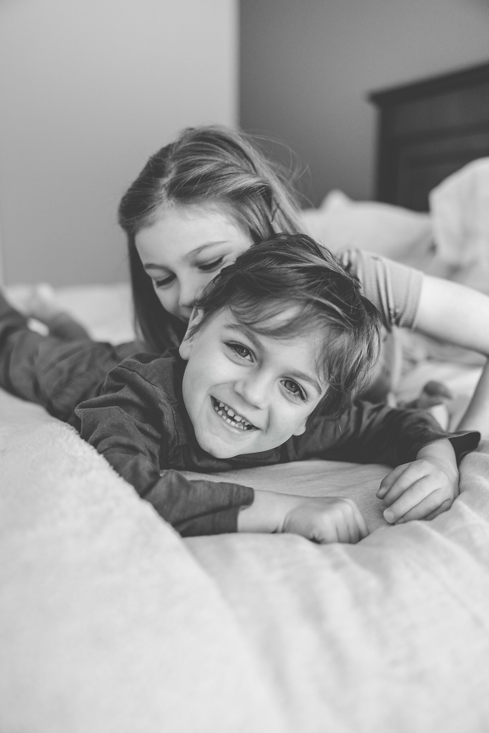 siblings play on bed together during Baltimore in-home family photos