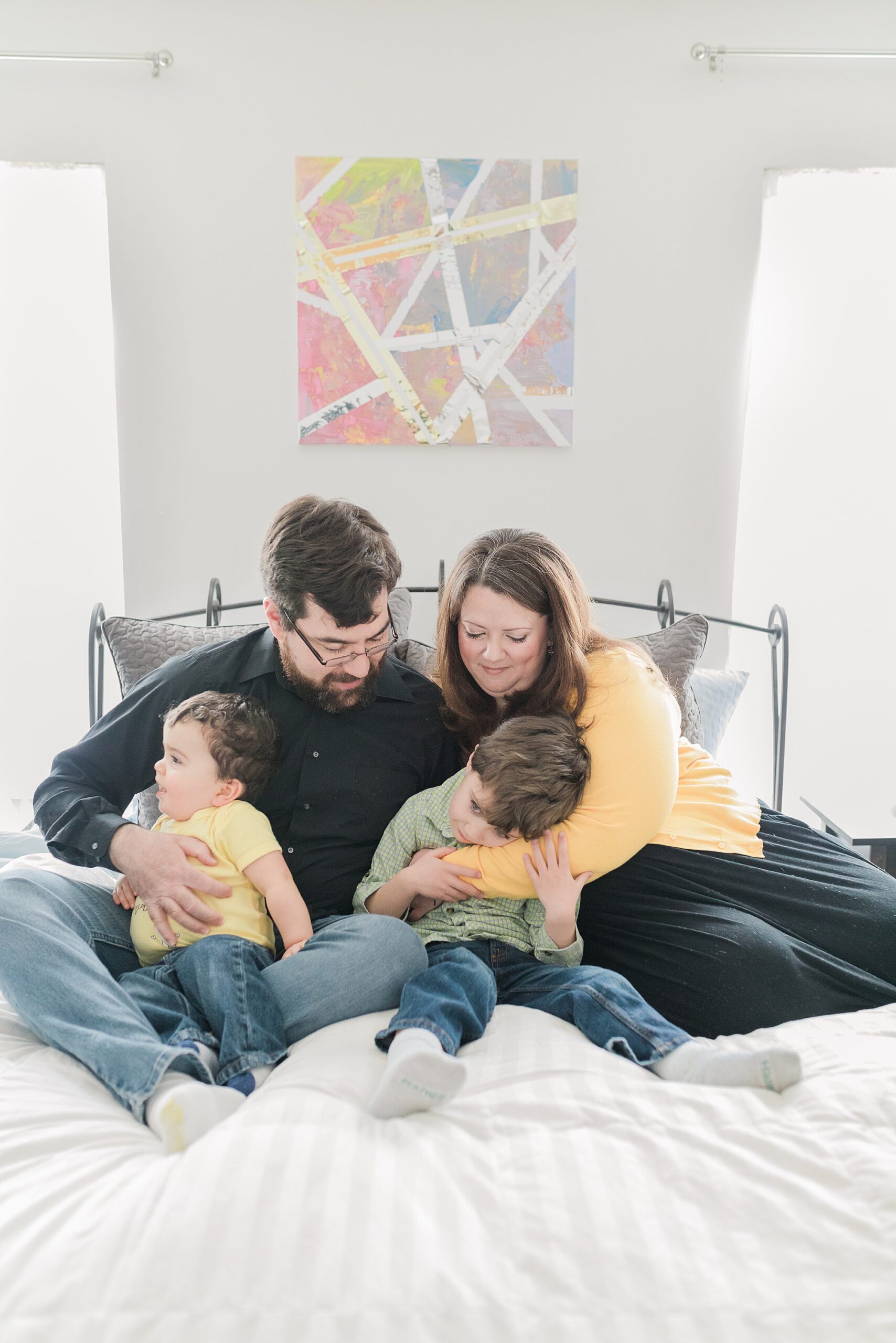 family sits together hugging on bed during lifestyle family photo session 
