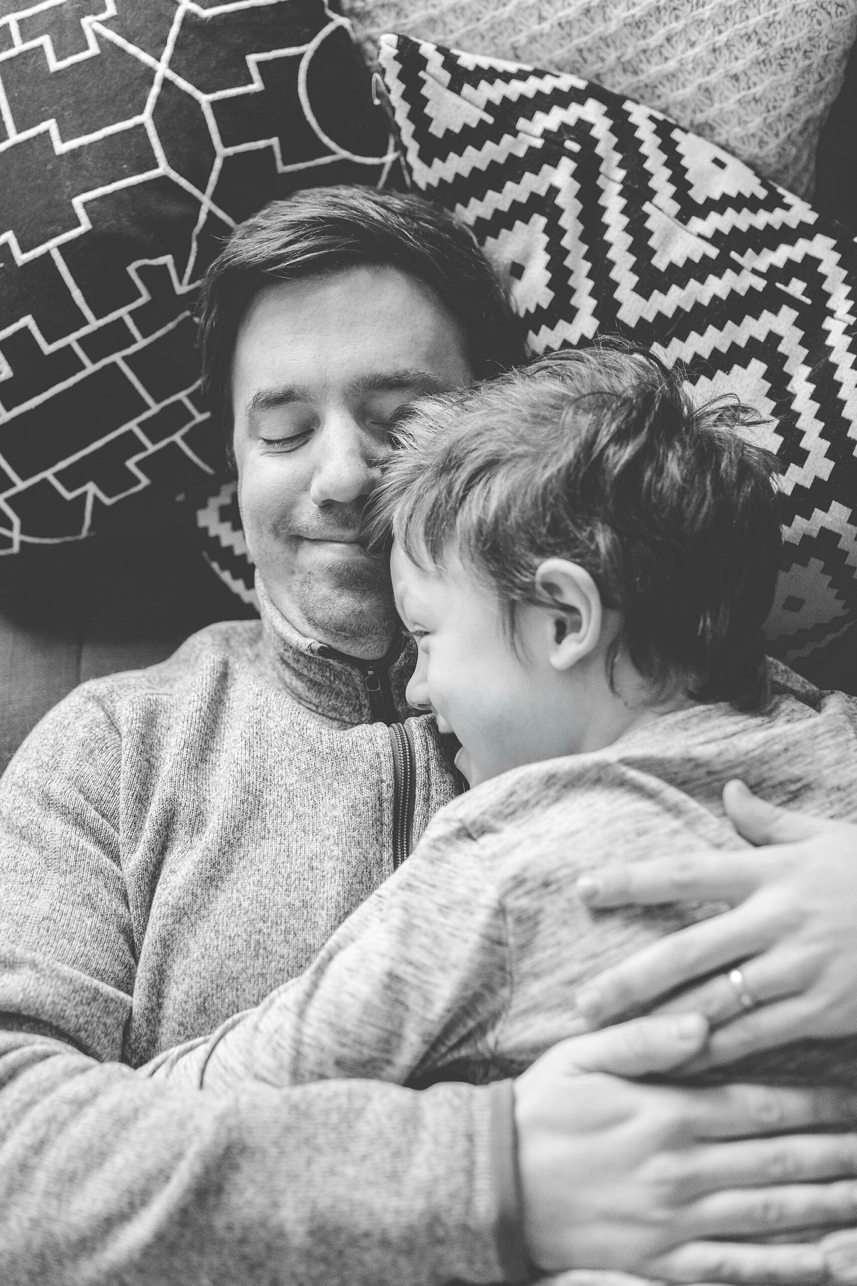 dad snuggles with son on couch during lifestyle family photos in Maryland