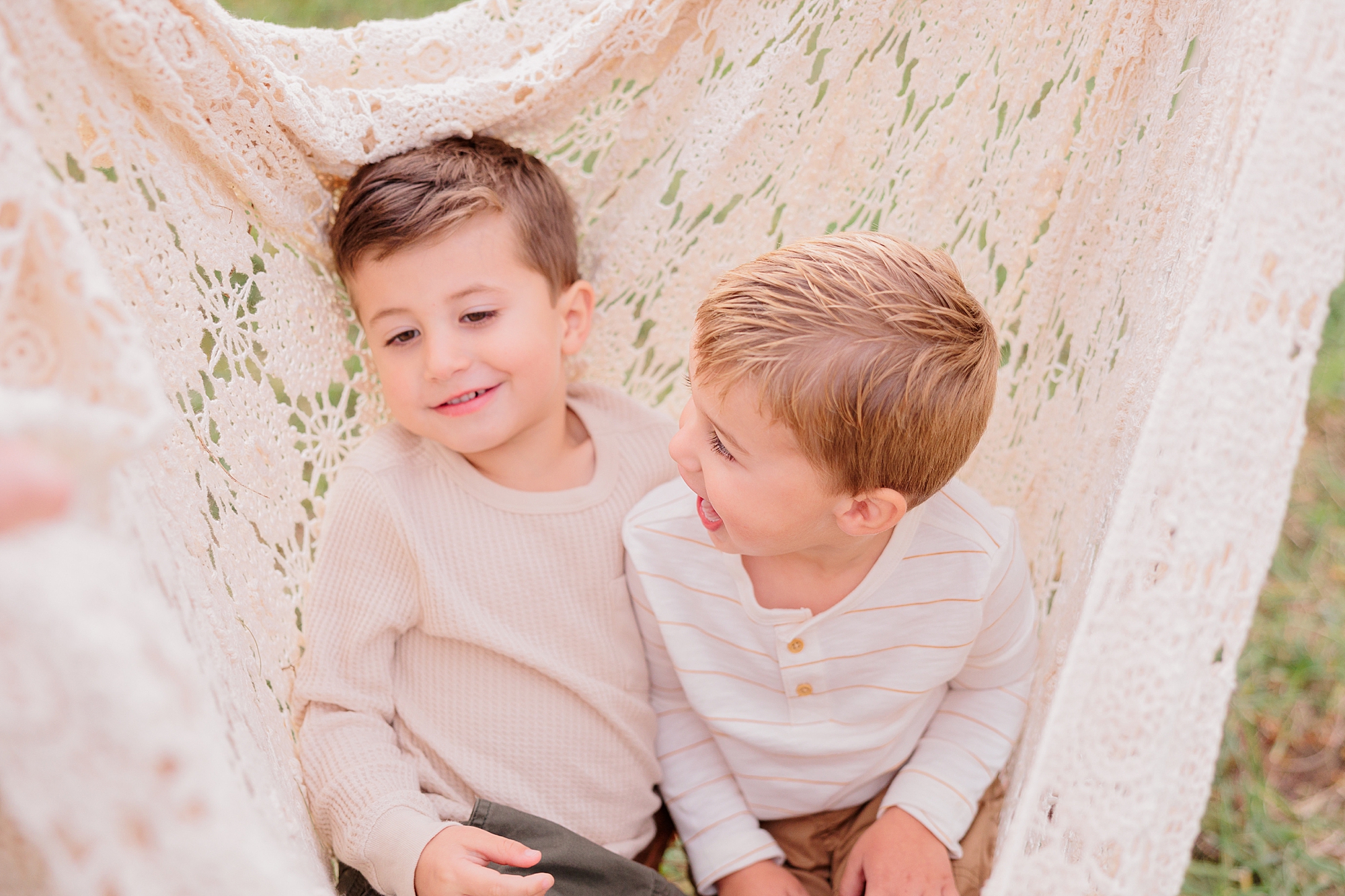 brothers play against ivory blanket during fall family photos