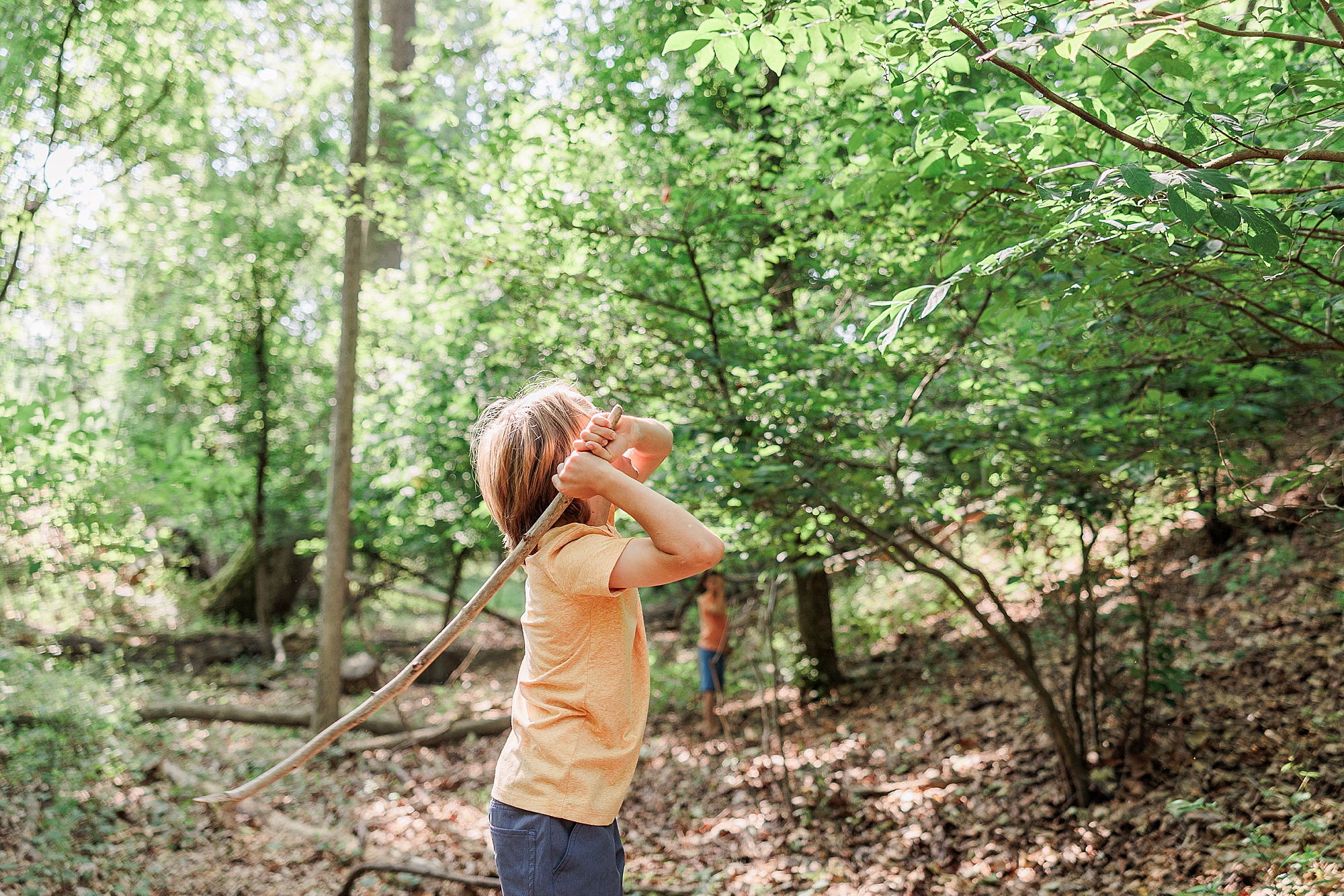 boy plays with stick in woods during Patapsco State Park family photos