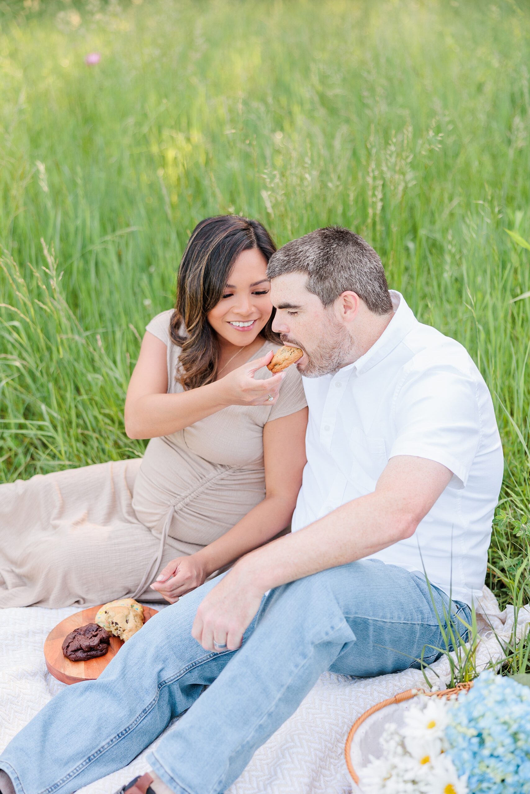 expecting woman feeds husband during picnic in Seneca Creek Park