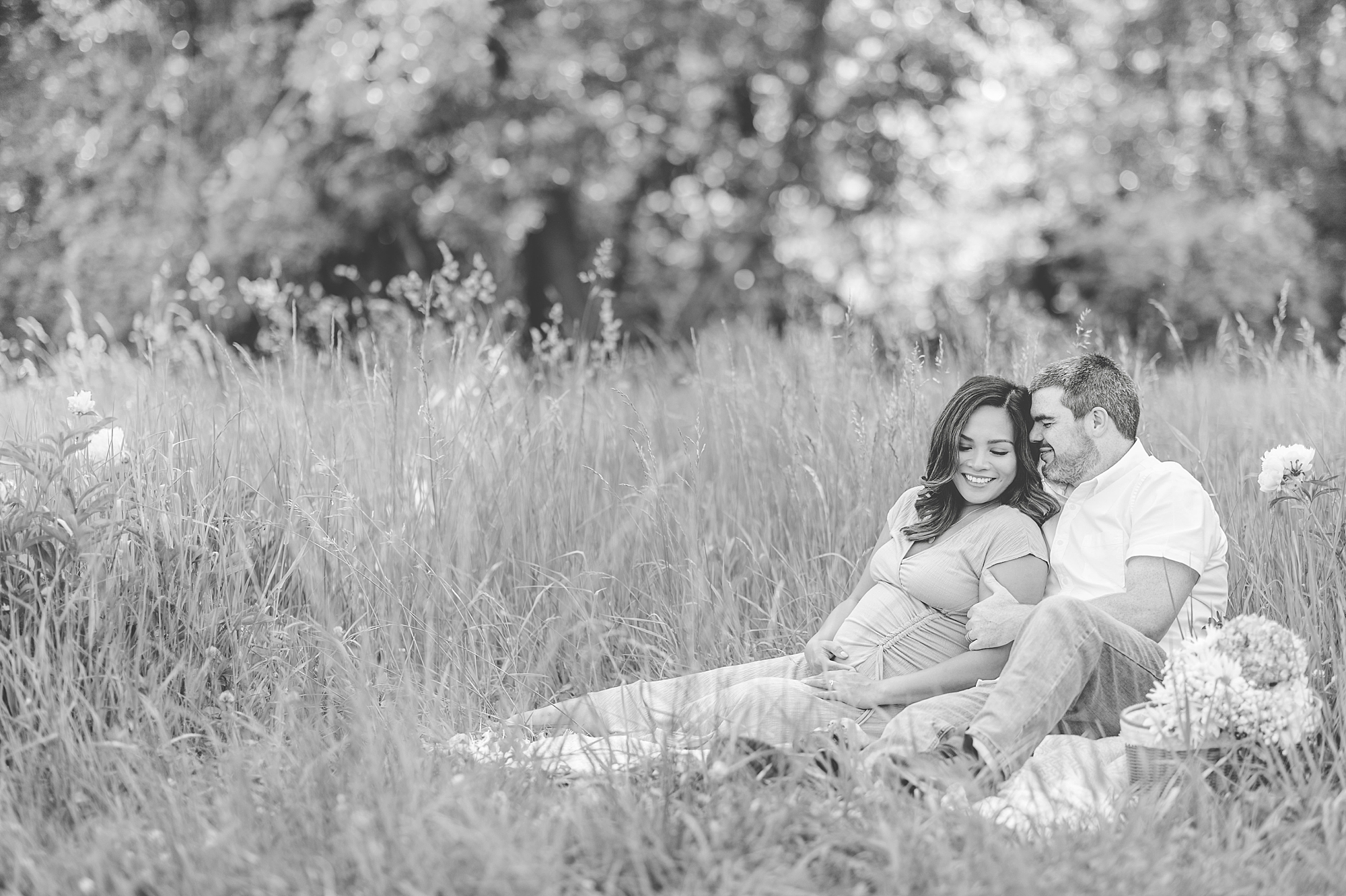 couple hugs sitting together on picnic blanket during Seneca Creek Park maternity session