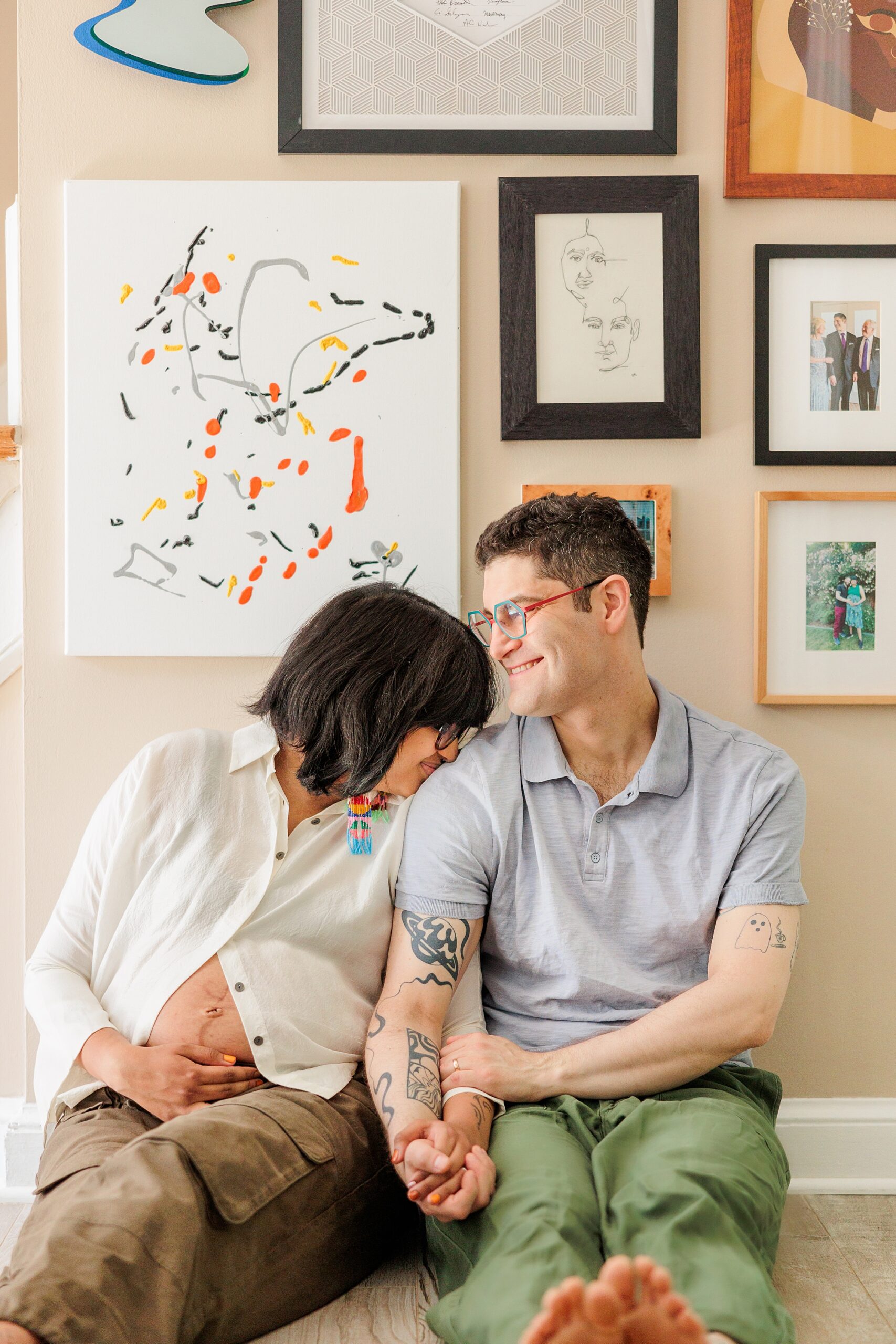 woman laughs leaning into husband's shoulder sitting on floor during Silver Spring Maternity lifestyle photos