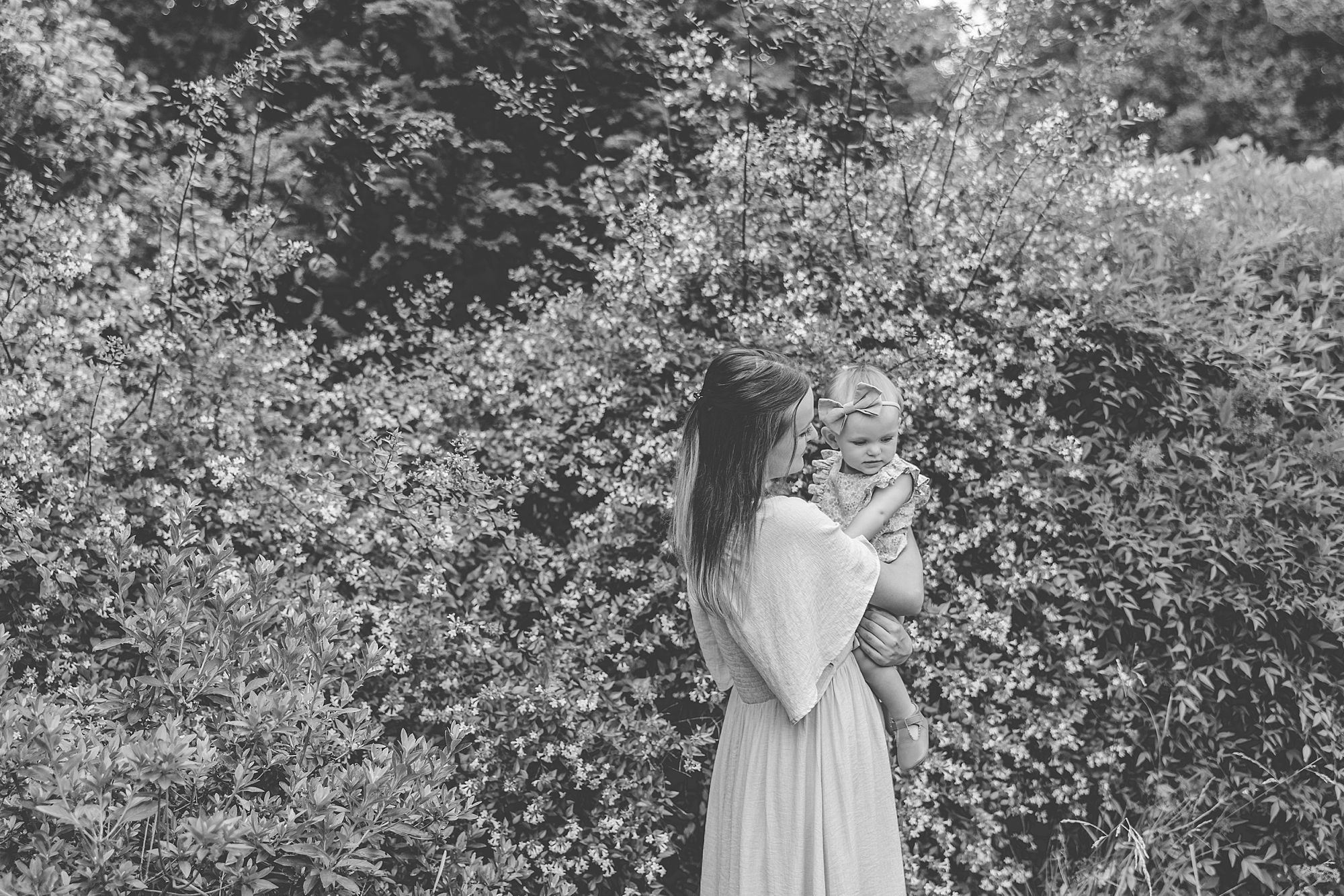 black and white photo of woman and daughter by wall of greenery at Tudor Place family photos