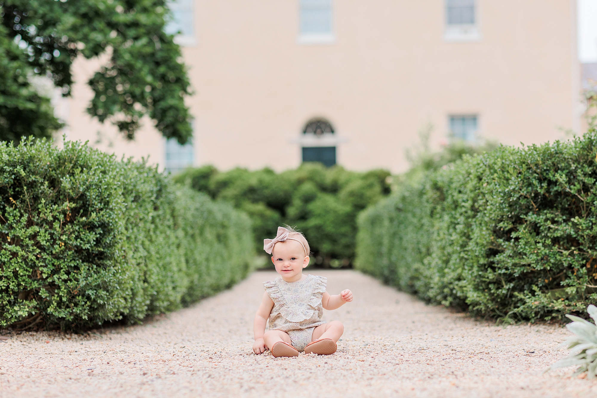 toddler sits on driveway playing during Tudor Place family photos