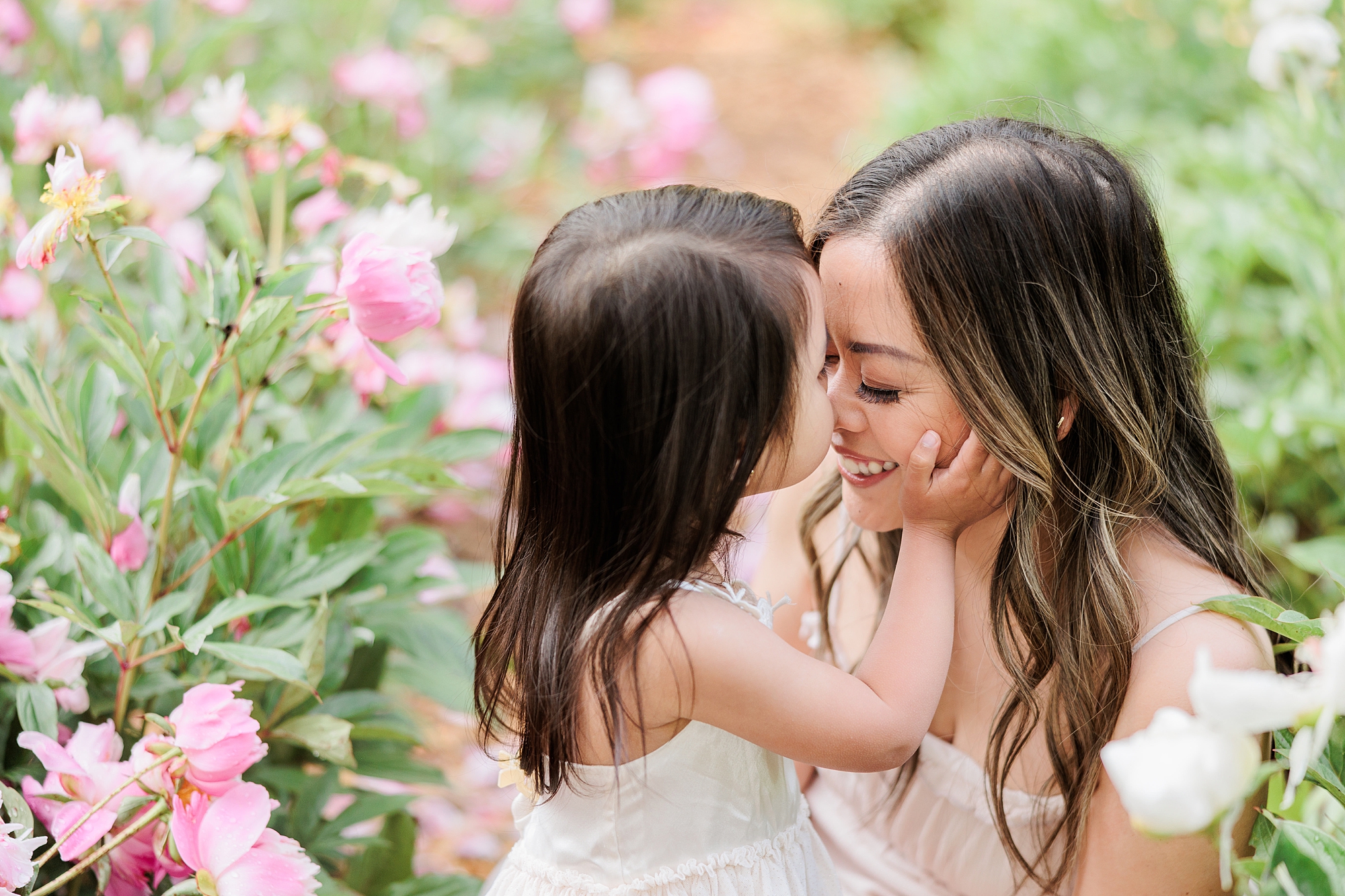 woman and toddler hug between peonies during mommy & me photos