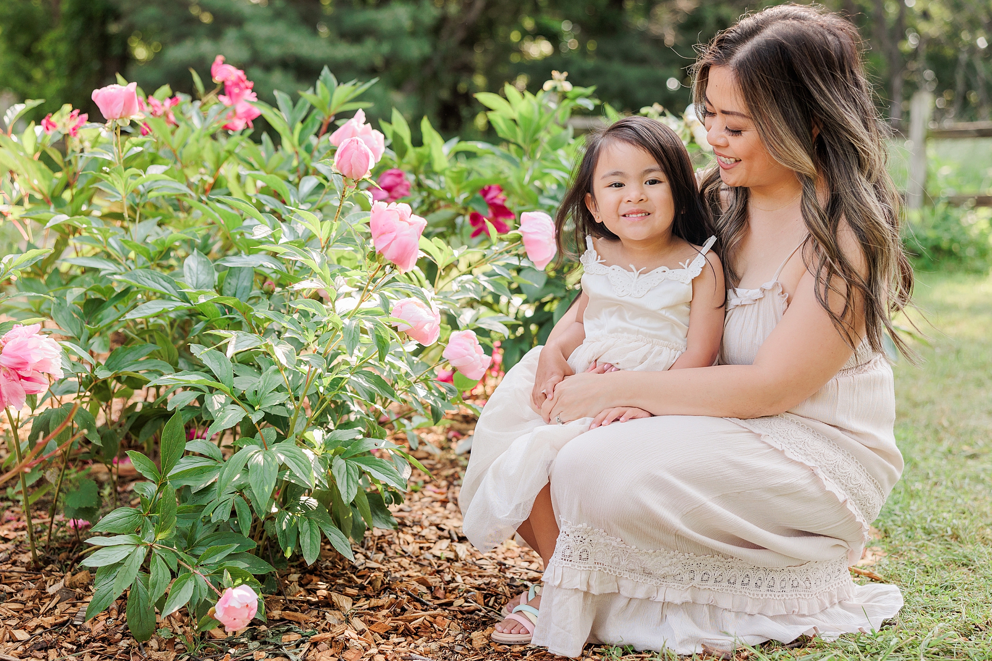 mom and daughter sit looking at flowers during mommy & me photos