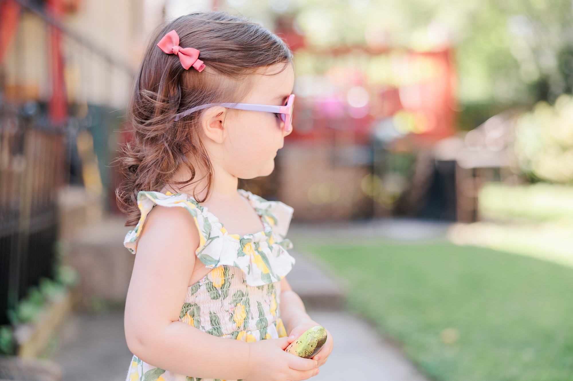 toddler in pink sunglasses stands in backyard