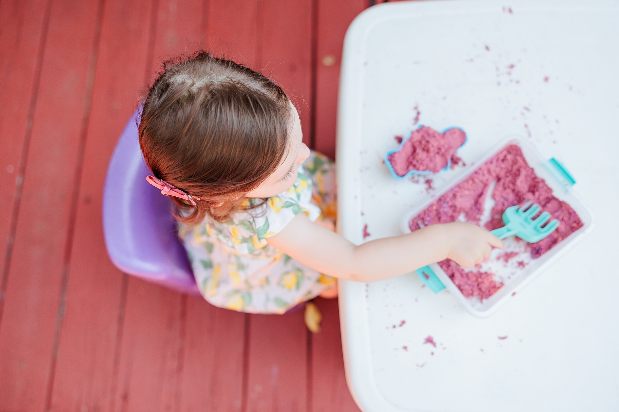 toddler plays with kinetic sand on backyard deck 