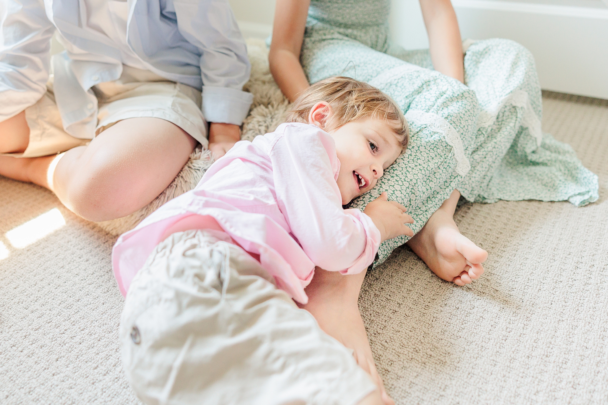 three year old lays on sister's leg during Maryland family photos