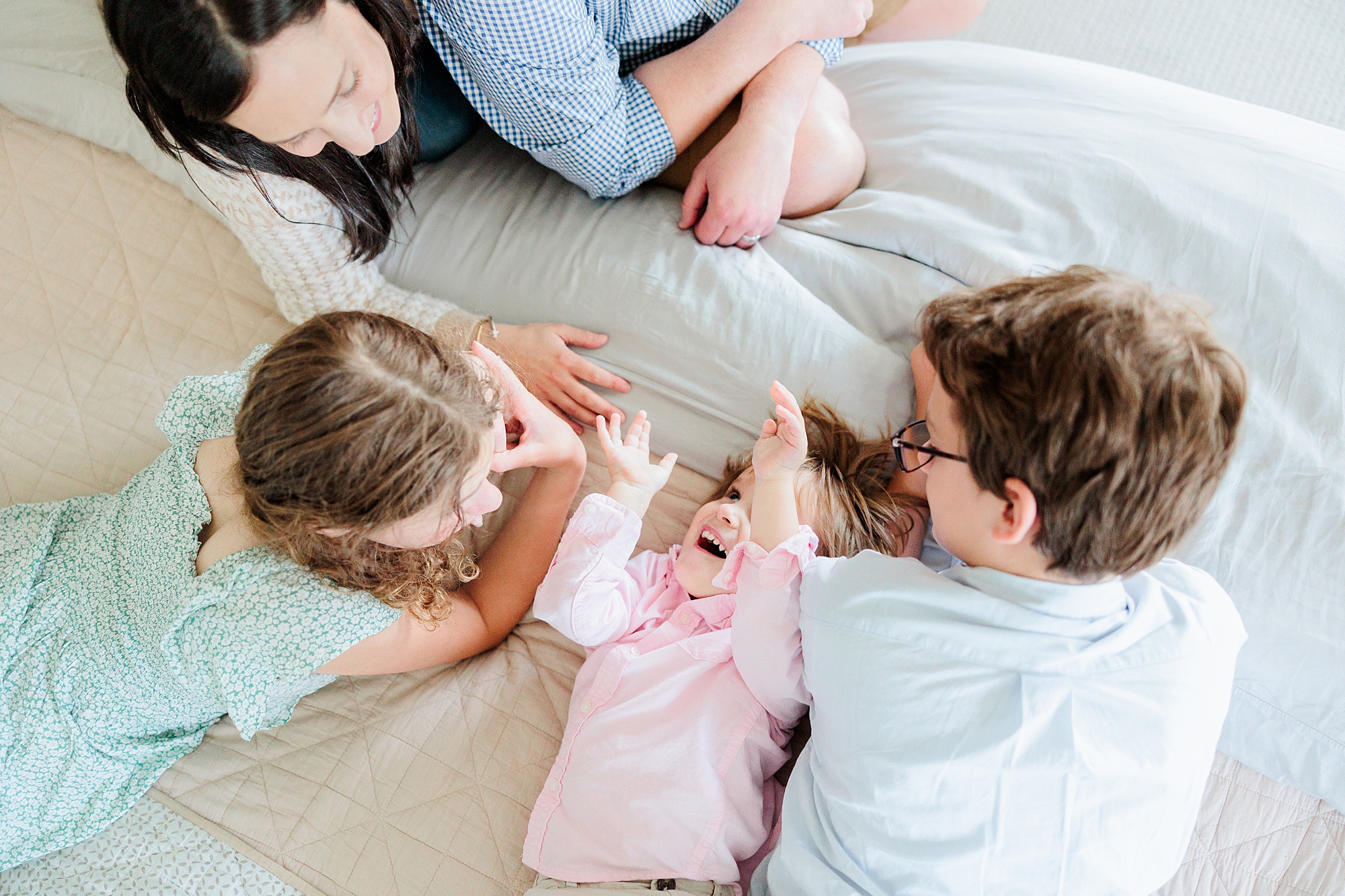 kids laugh on parents' bed during family photos in Clarksville MD