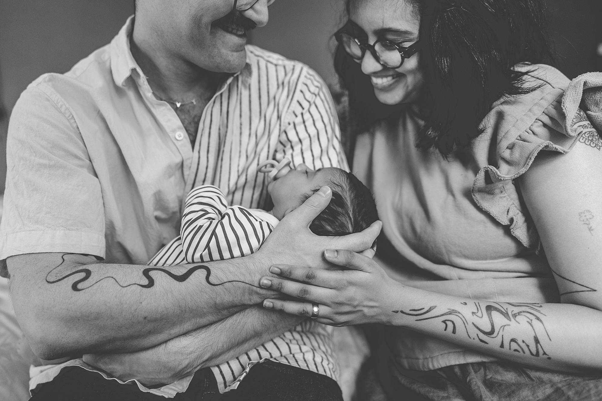 new parents smile down at baby girl during newborn portraits at home in Silver Spring MD