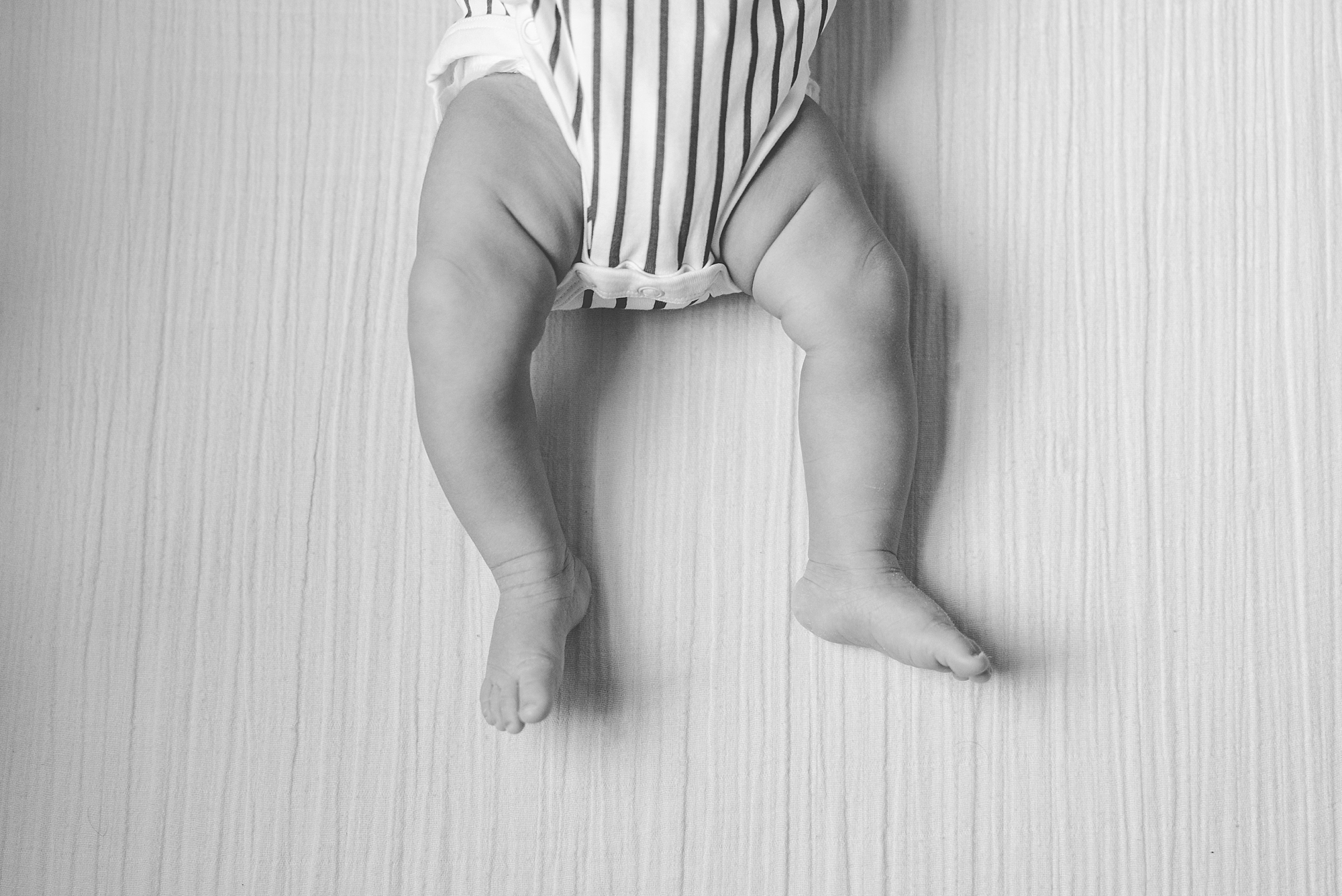 baby girl lays in striped onesie during lifestyle newborn portraits in Silver Spring MD