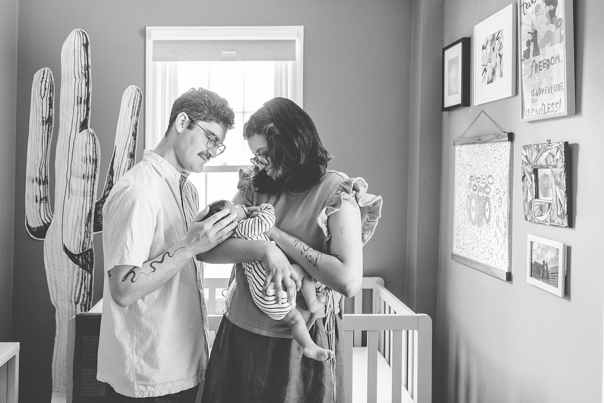 new parents hold baby by crib looking down at her during lifestyle newborn portraits in Silver Spring MD