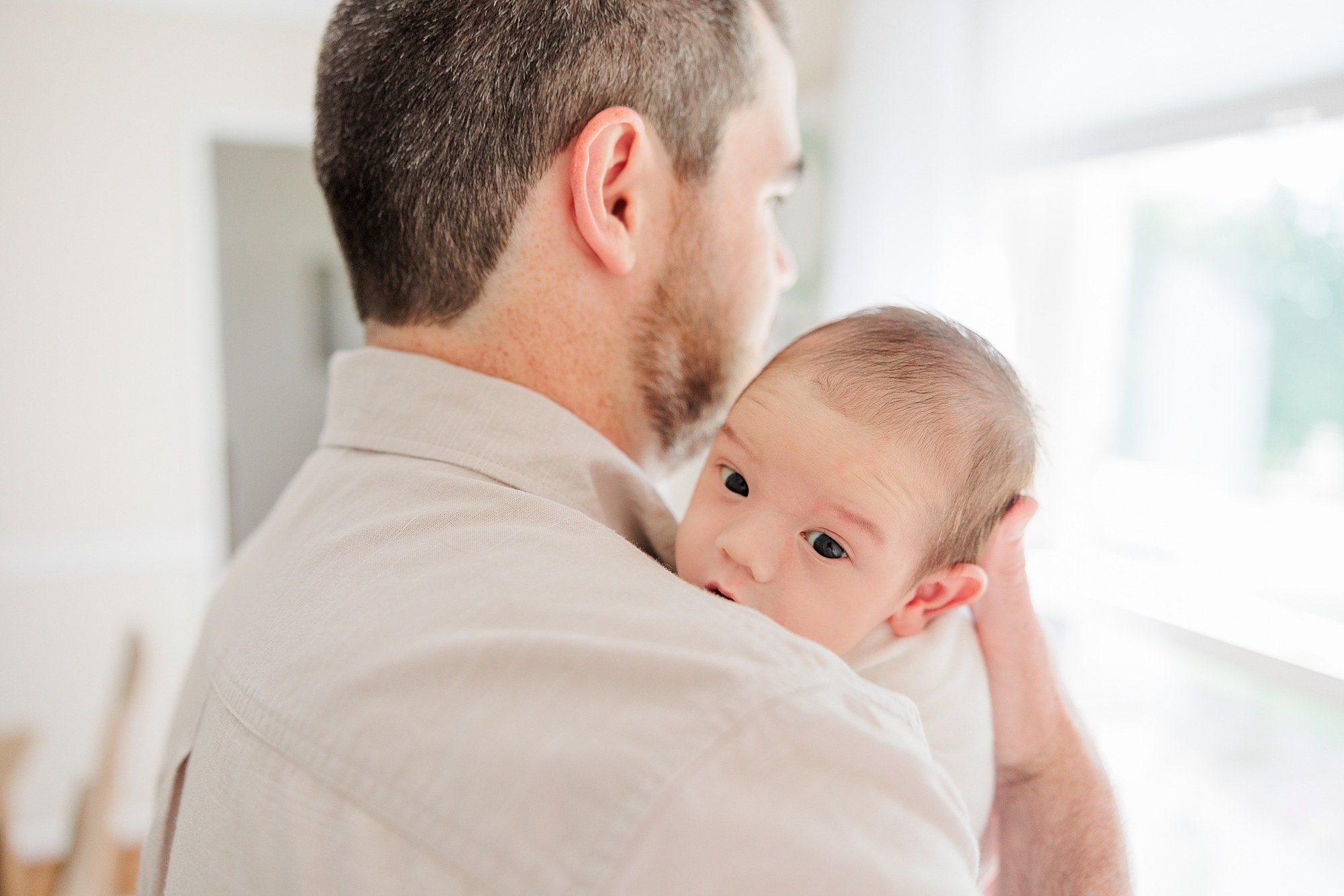 baby looks over dad's shoulder during VA newborn session