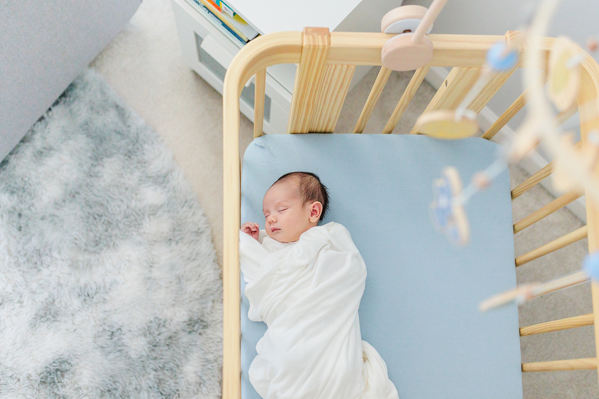 baby in white wrap lays on blue crib sheet