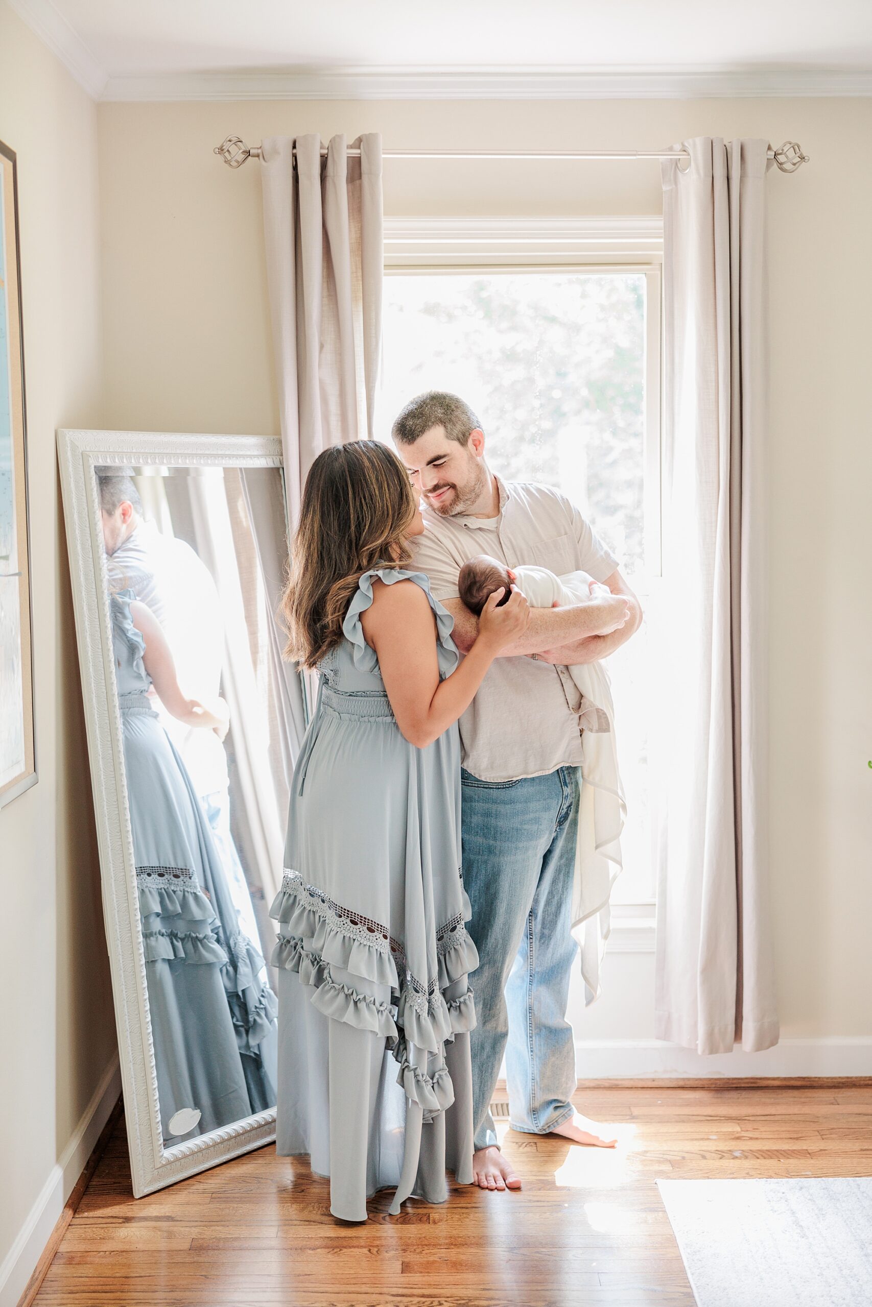 parents kiss holding son in bedroom by mirror