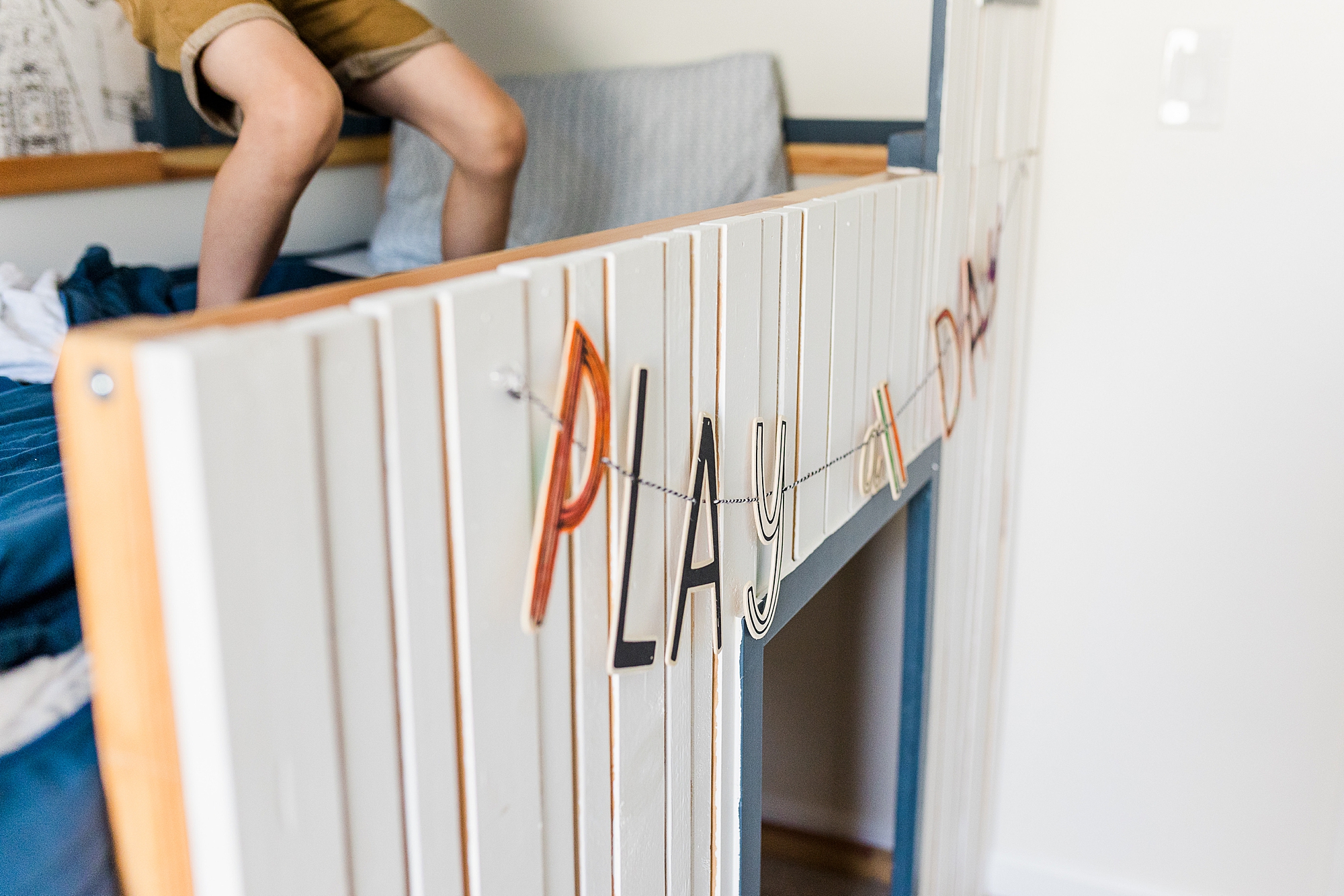 kids sit on bed with PLAY sign hanging at home during family photos 