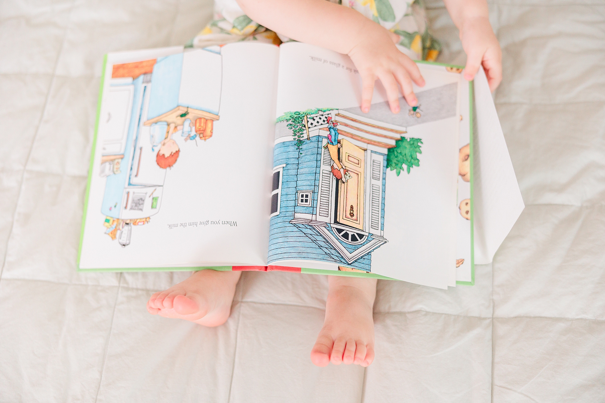 toddler reads on bed during family photos at home 