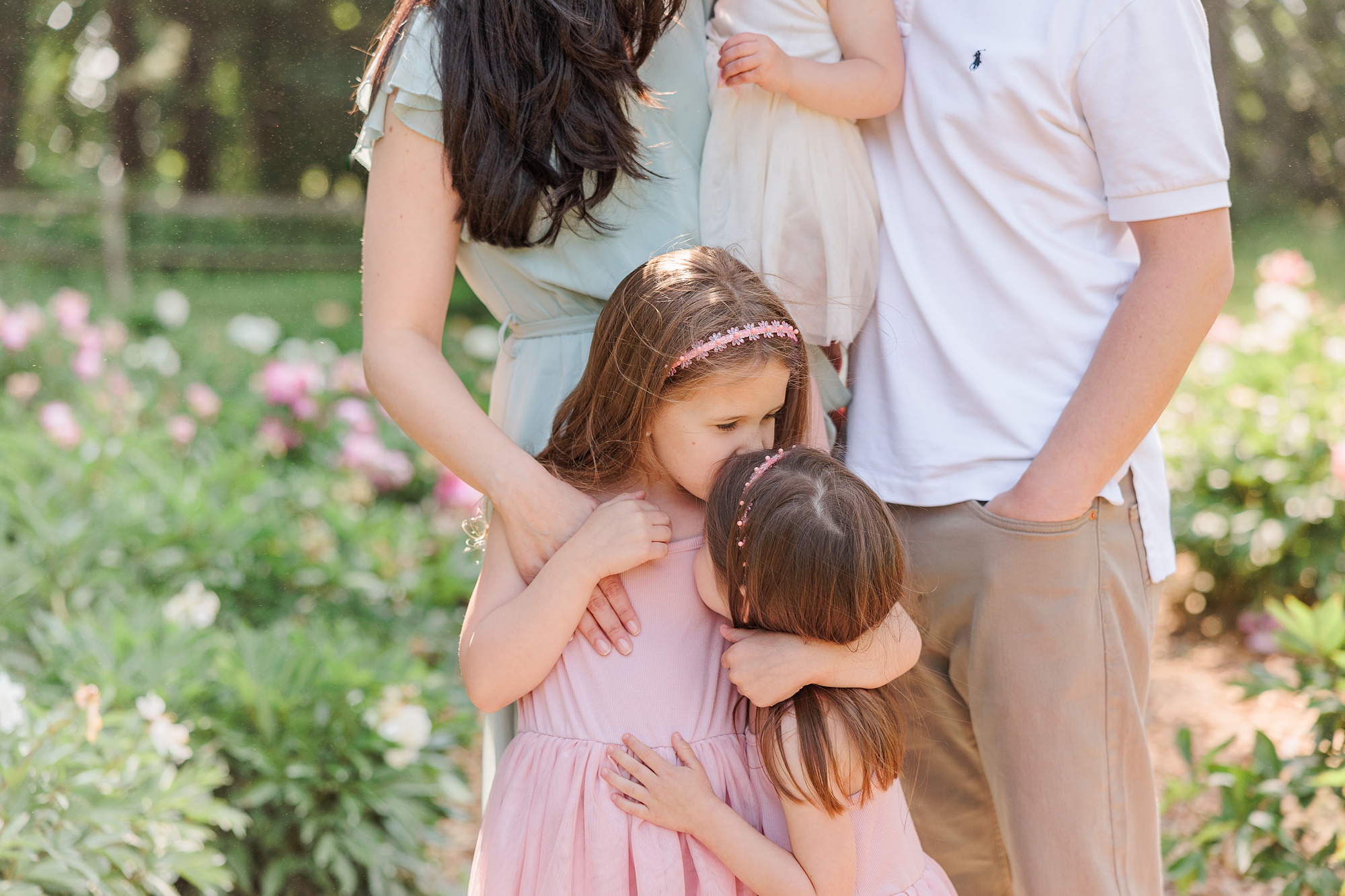 sisters hug and kiss during spring family photos in Maryland 