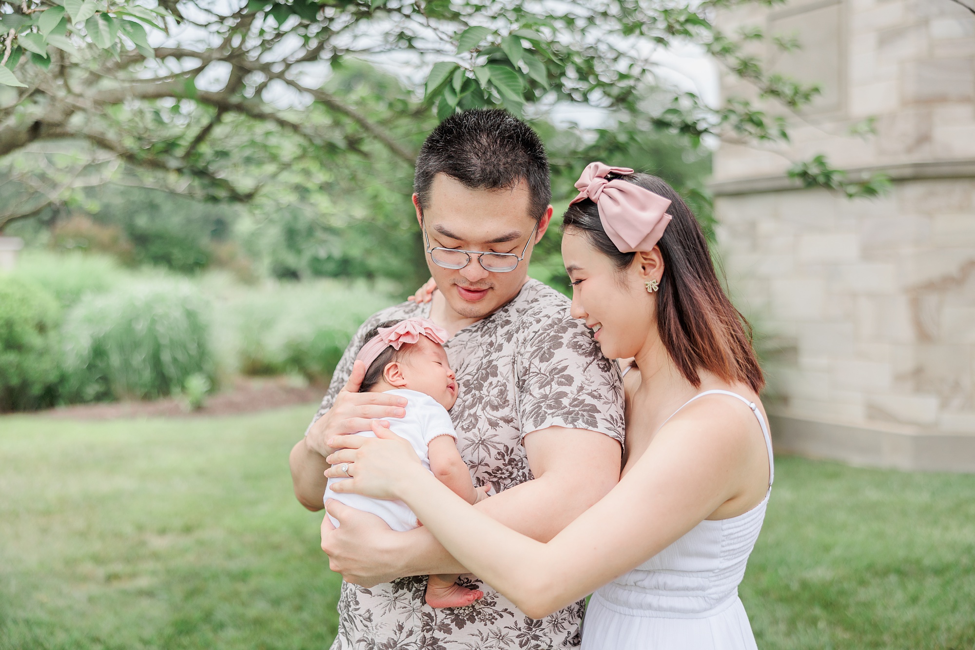 couple hugs with newborn baby girl between them during Maryland family photos