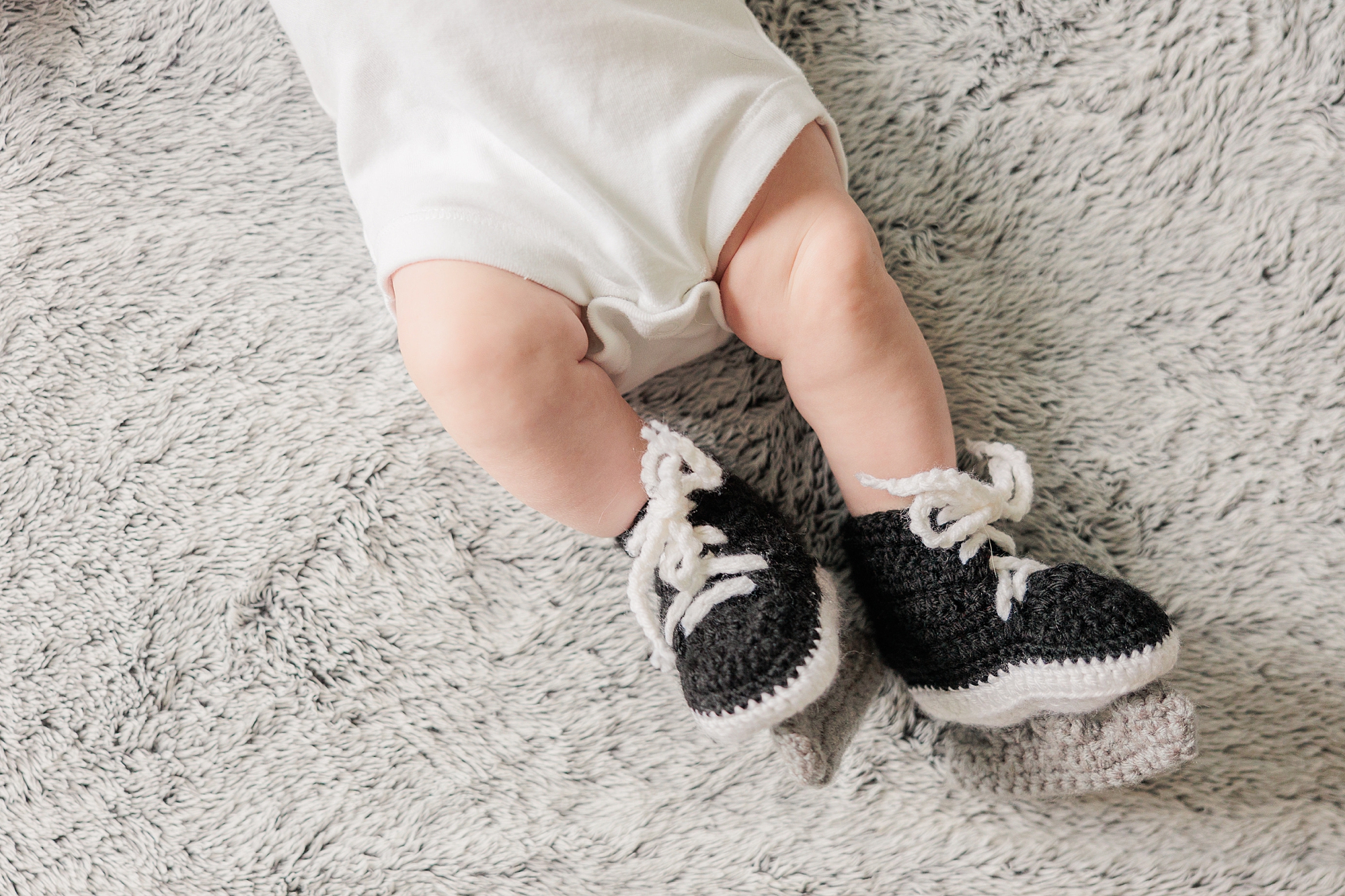 baby lays with knit shoes on their feet 
