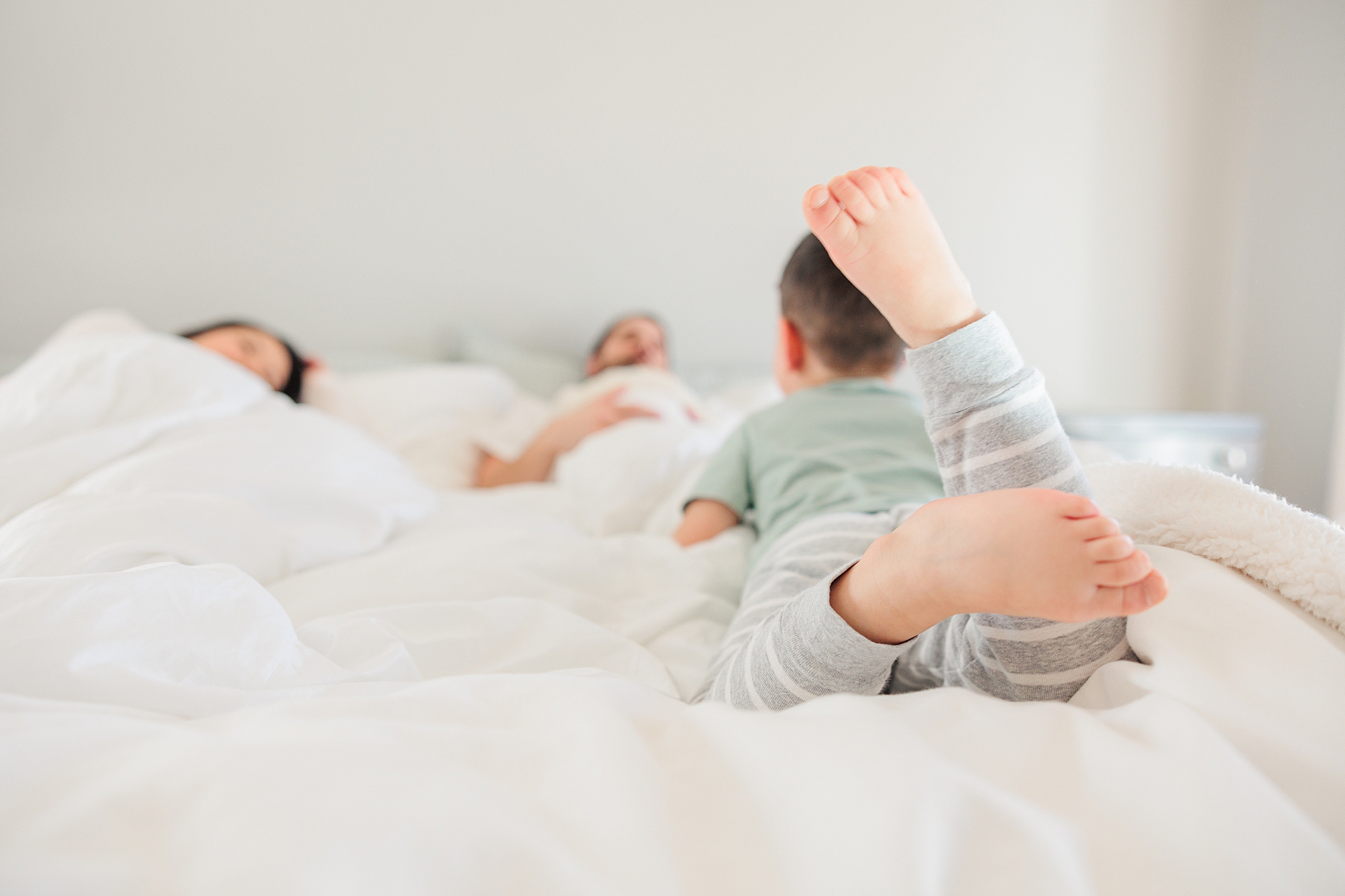 toddler lays on end of bed with feet in the air during Howard County newborn and family lifestyle photos