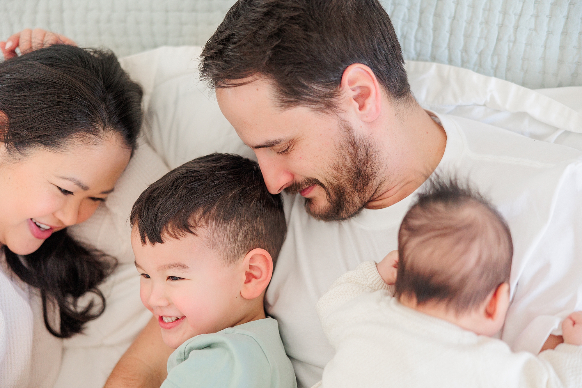 family of four snuggles in bed during Howard County newborn and family lifestyle photos