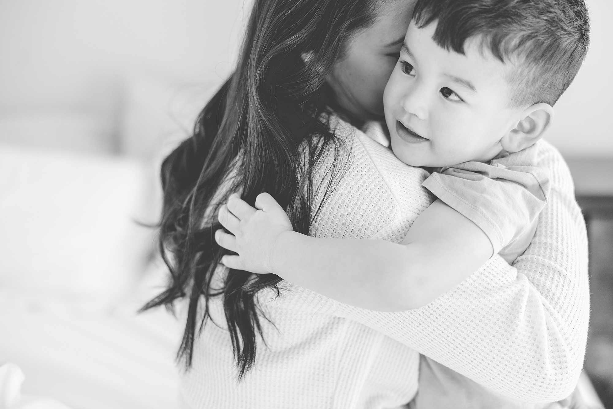 mom hugs toddler son in black and white photo