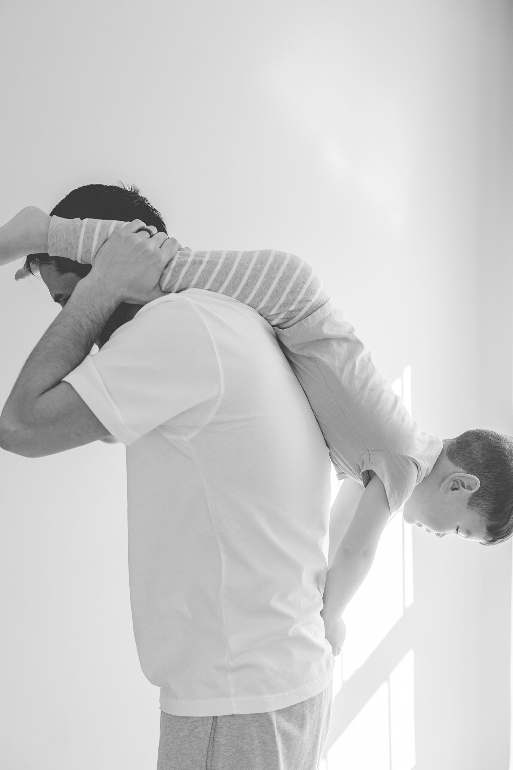 dad lifts son over his back playing during family photos at home in Howard County