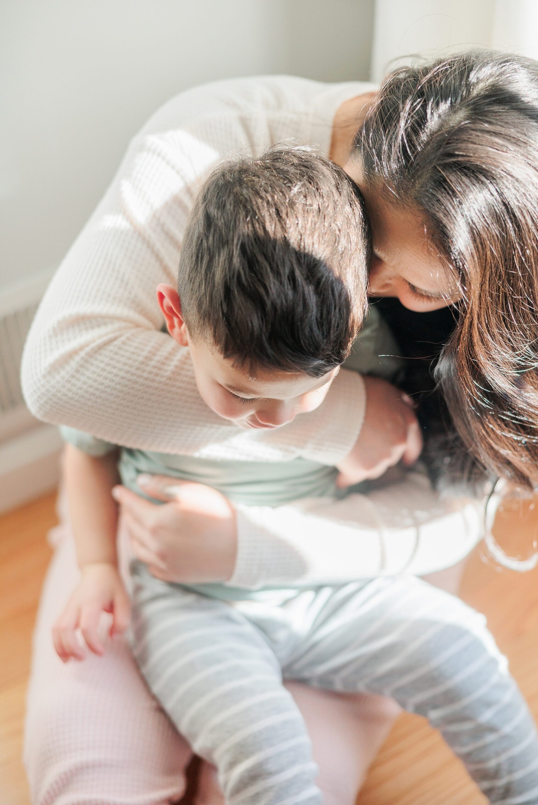 mom and son hug in living room with light across their heads 