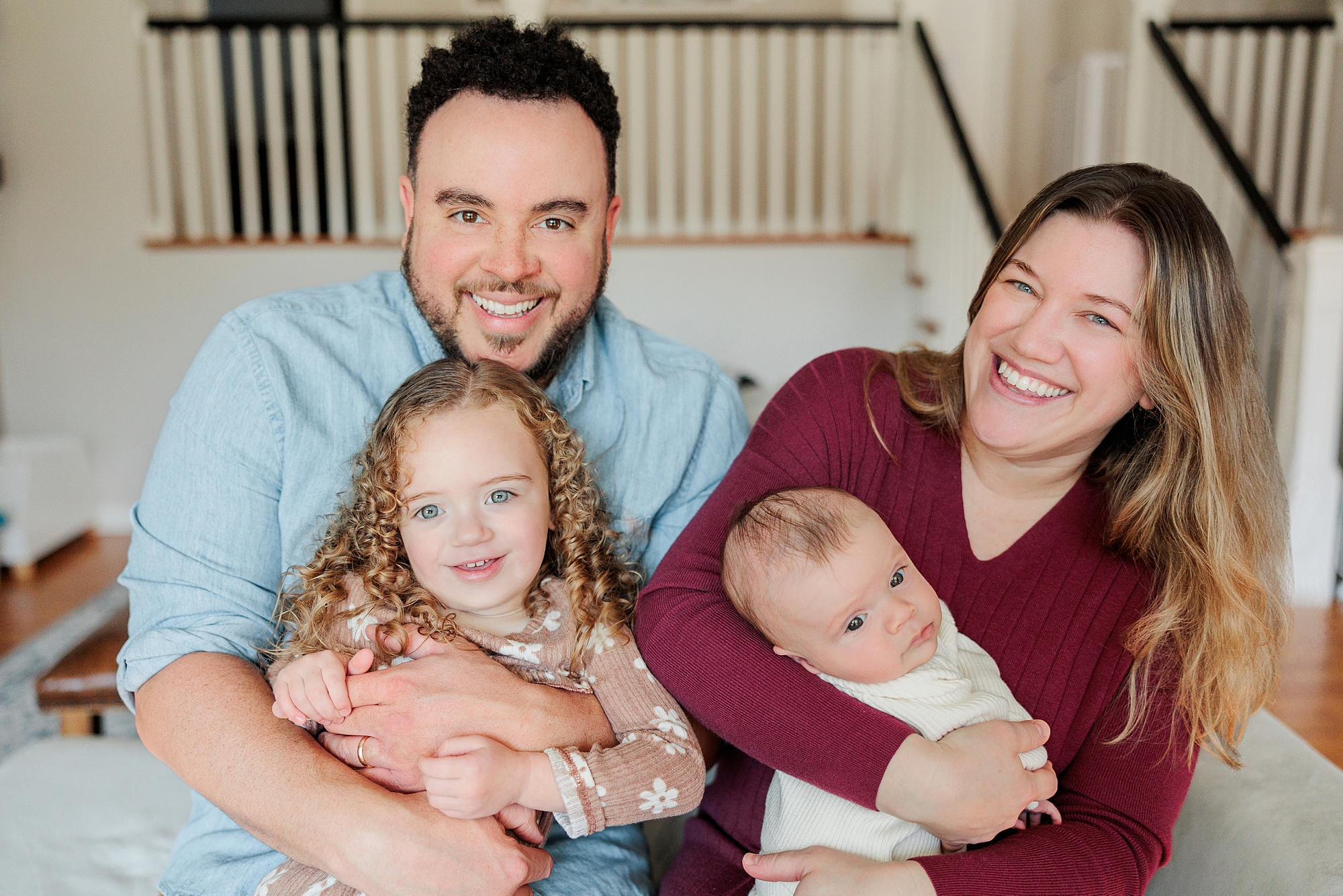 parents laugh holding two daughters during Maryland newborn lifestyle session