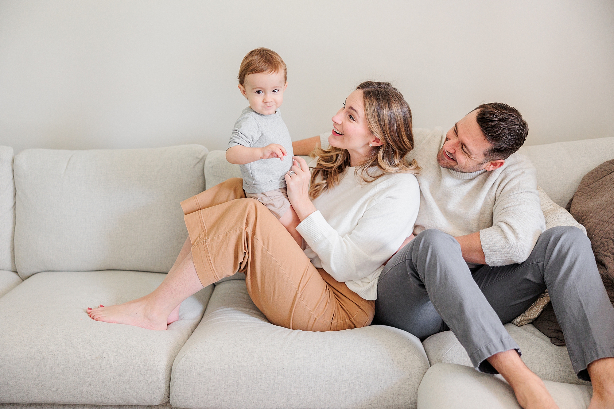 parents sit on couch with toddler son during family photos in Maryland 