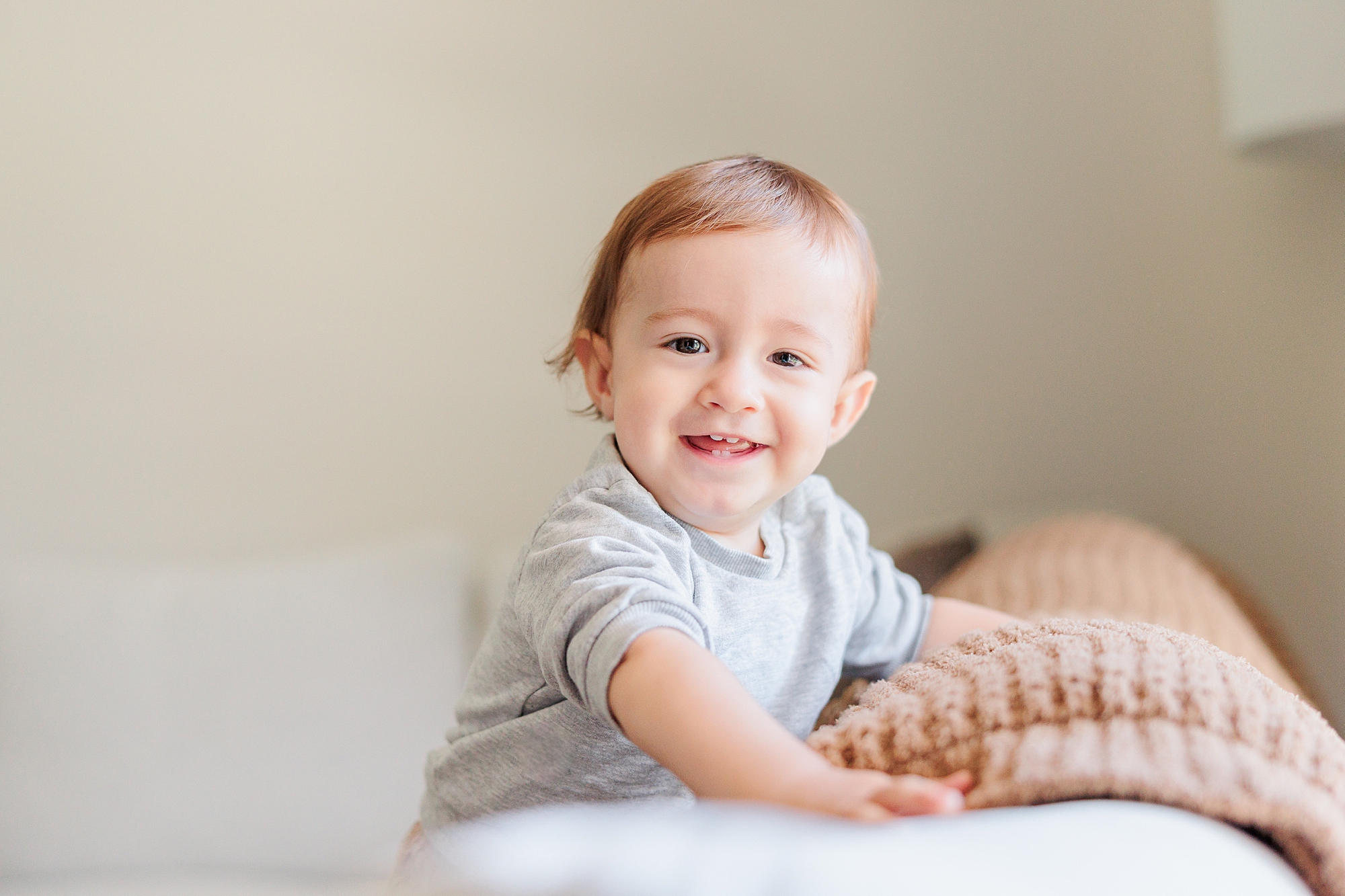 baby leans against bed during lifestyle family photos at home 