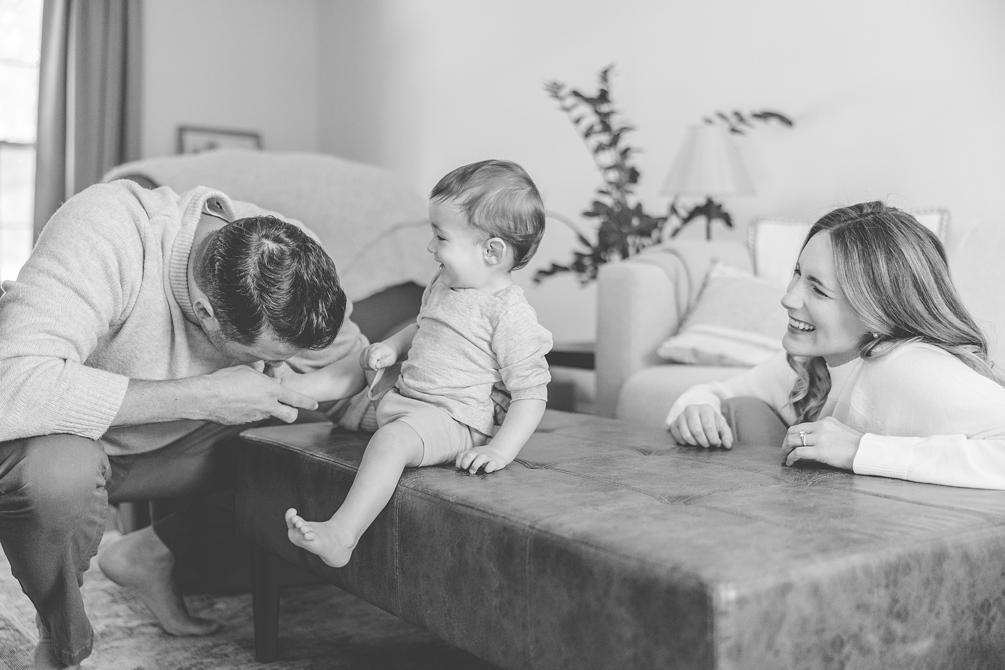 parents play with baby on table in front couch during lifestyle family photos 